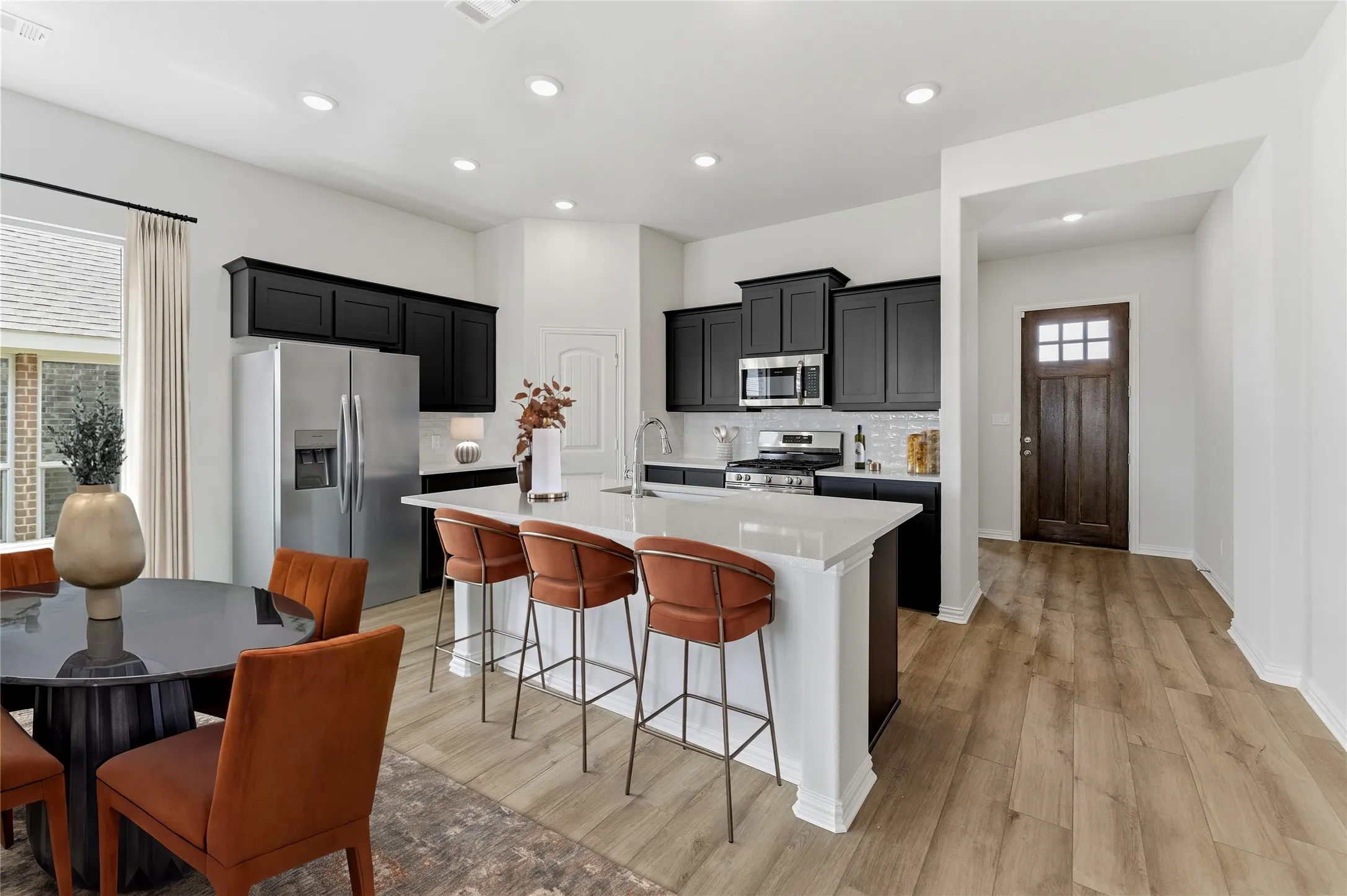Kitchen featuring dark wood cabinetry, white countertops, stainless steel appliances, and wood-finish flooring