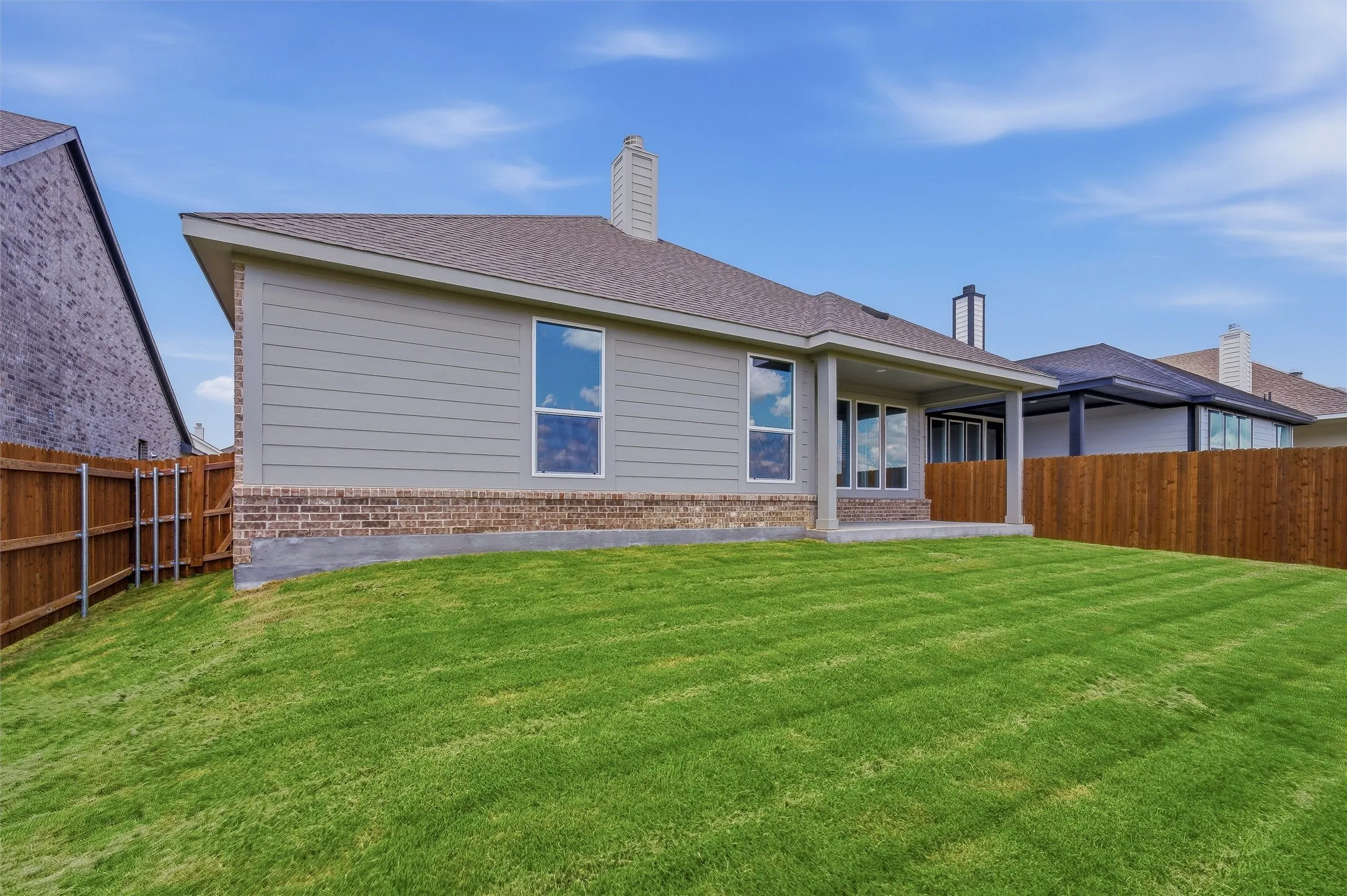 Expansive backyard featuring a manicured lawn, a covered patio, and a privacy fence