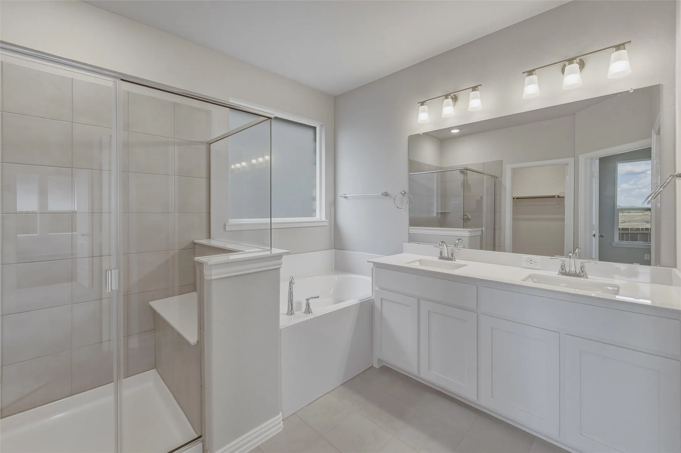 Bathroom featuring a dual vanity with white cabinetry and integrated sinks, a full-width mirror, and brushed nickel light fixtures