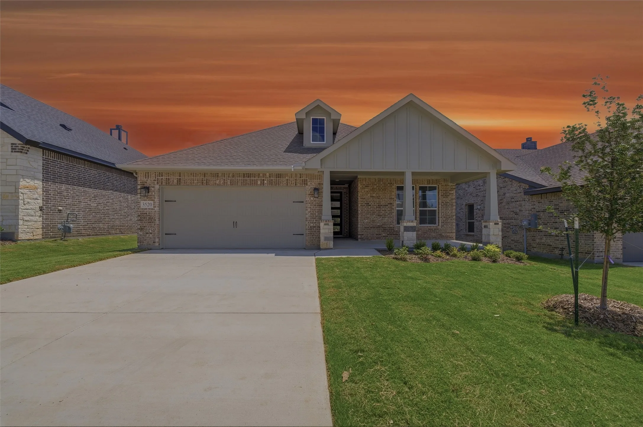 Brick and stone exterior featuring a covered entryway, gabled roofline, two-car garage, and a concrete driveway