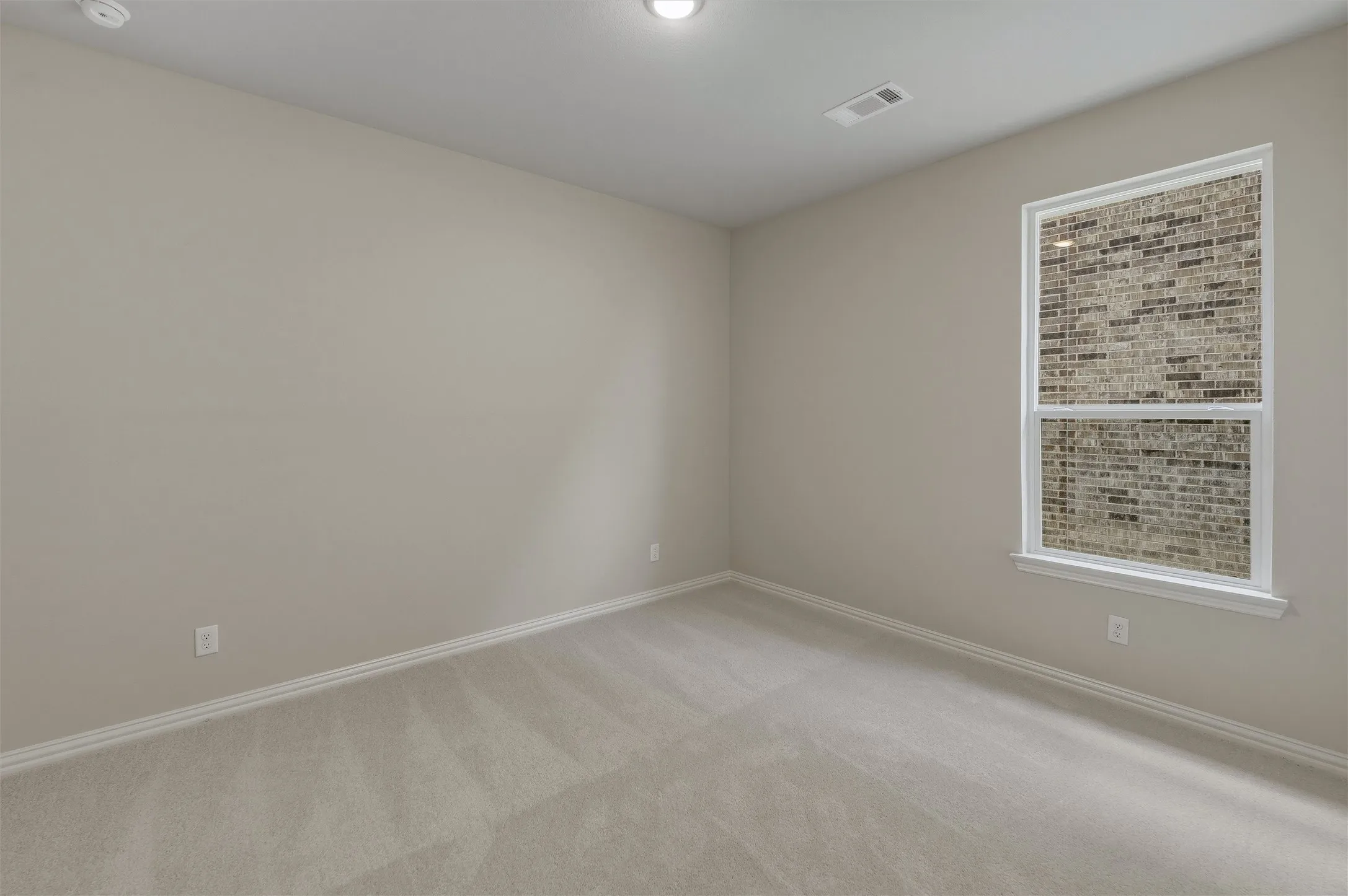 Spacious room with neutral-toned carpeting, light-colored walls, and crisp white baseboards