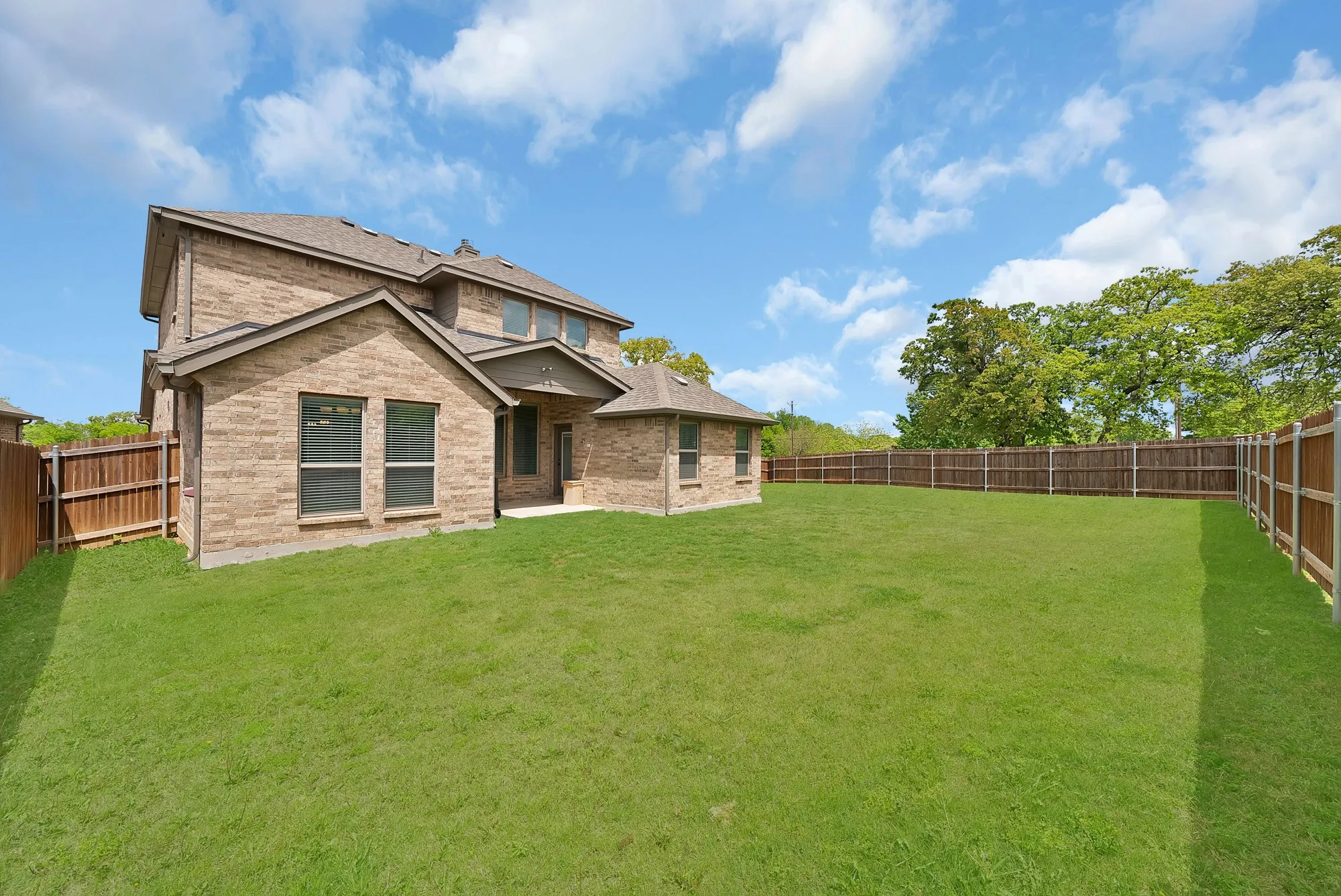 The property features an expansive, well-maintained lawn with a privacy fence