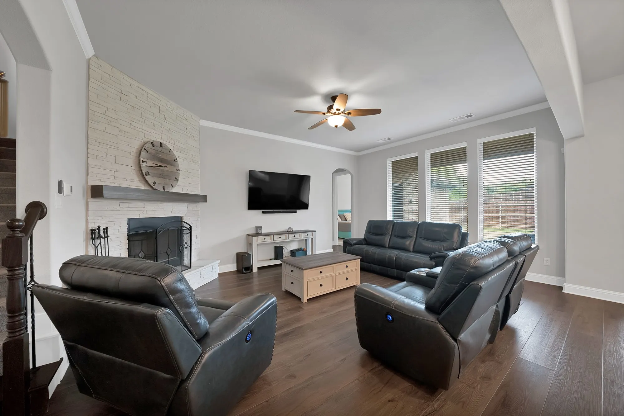 Living area featuring hardwood floors, a white brick fireplace with a mantle, and large windows with blinds