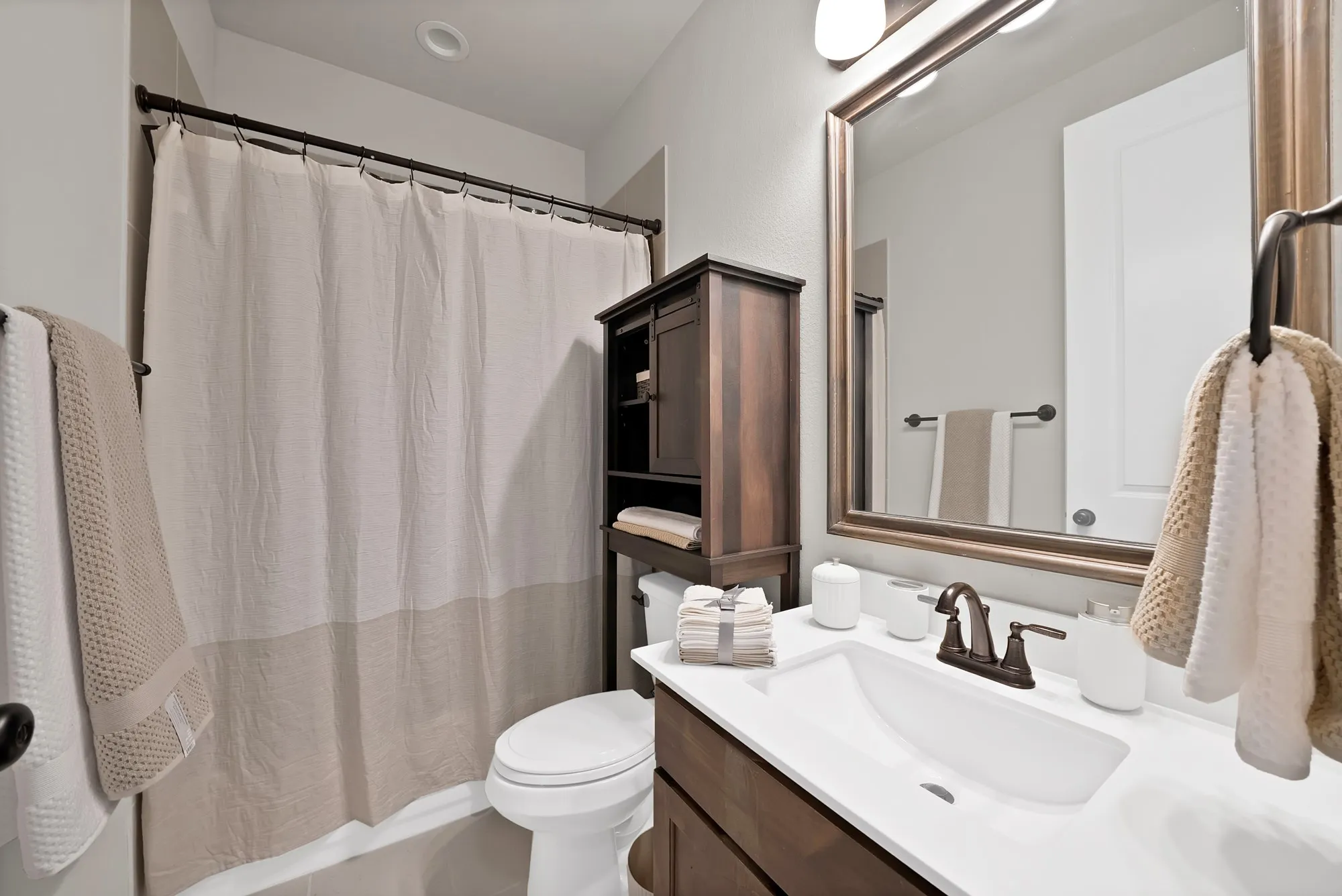 Bathroom featuring a vanity with a white countertop and a dark bronze faucet, a framed mirror, and a toilet
