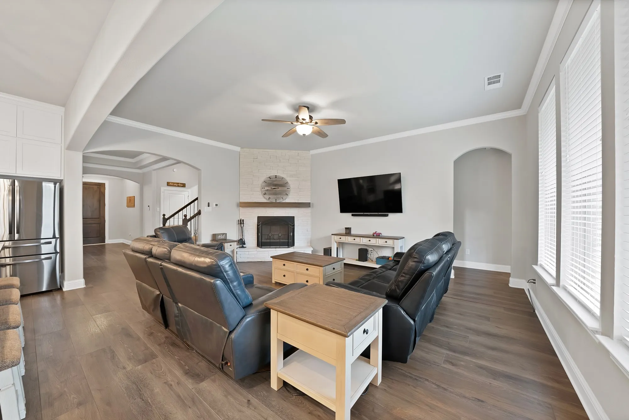 The living area features wood flooring, a fireplace with a light-colored brick surround and wooden mantel, and a ceiling fan