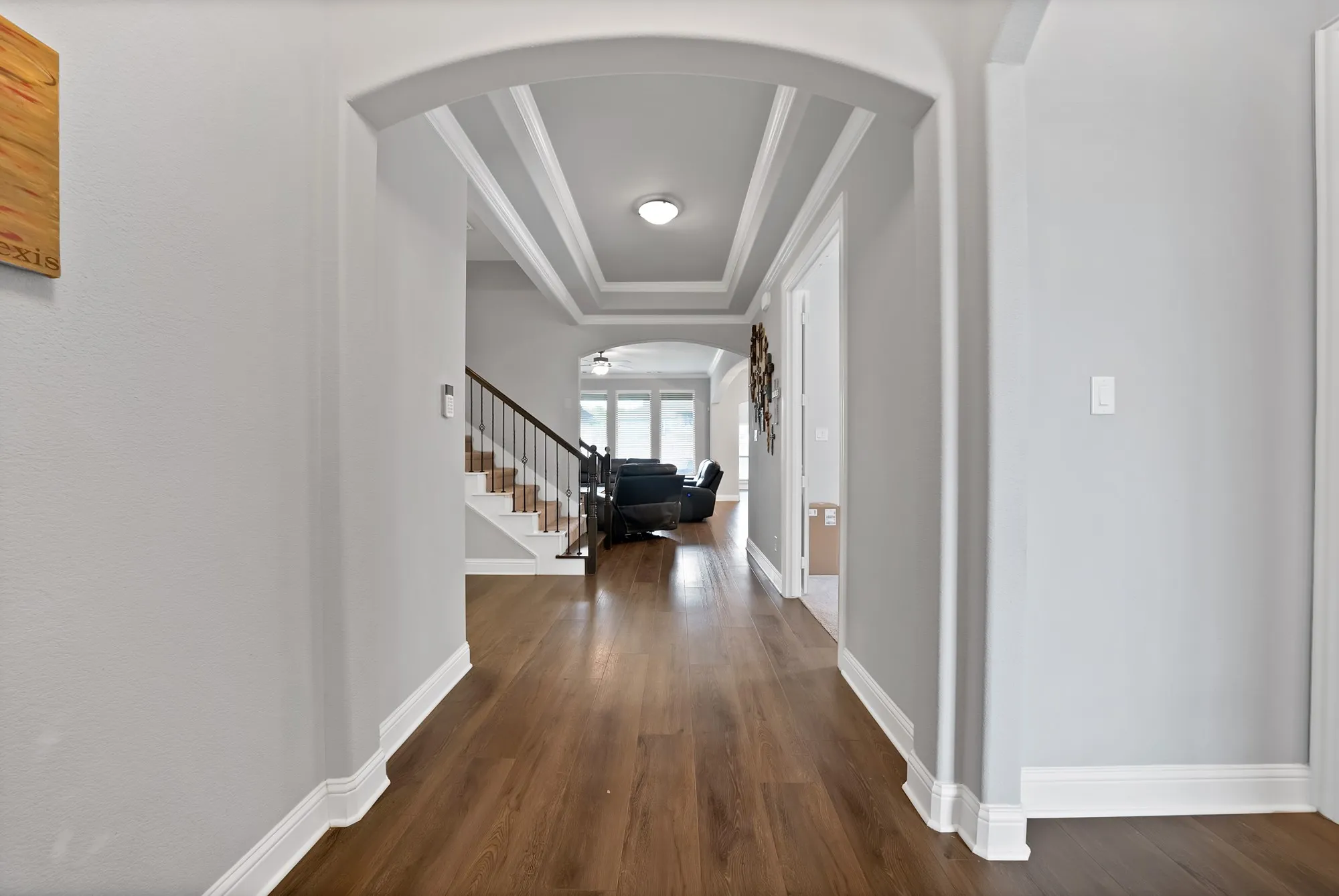 Inviting entryway featuring hardwood flooring, an arched doorway, and coffered ceilings