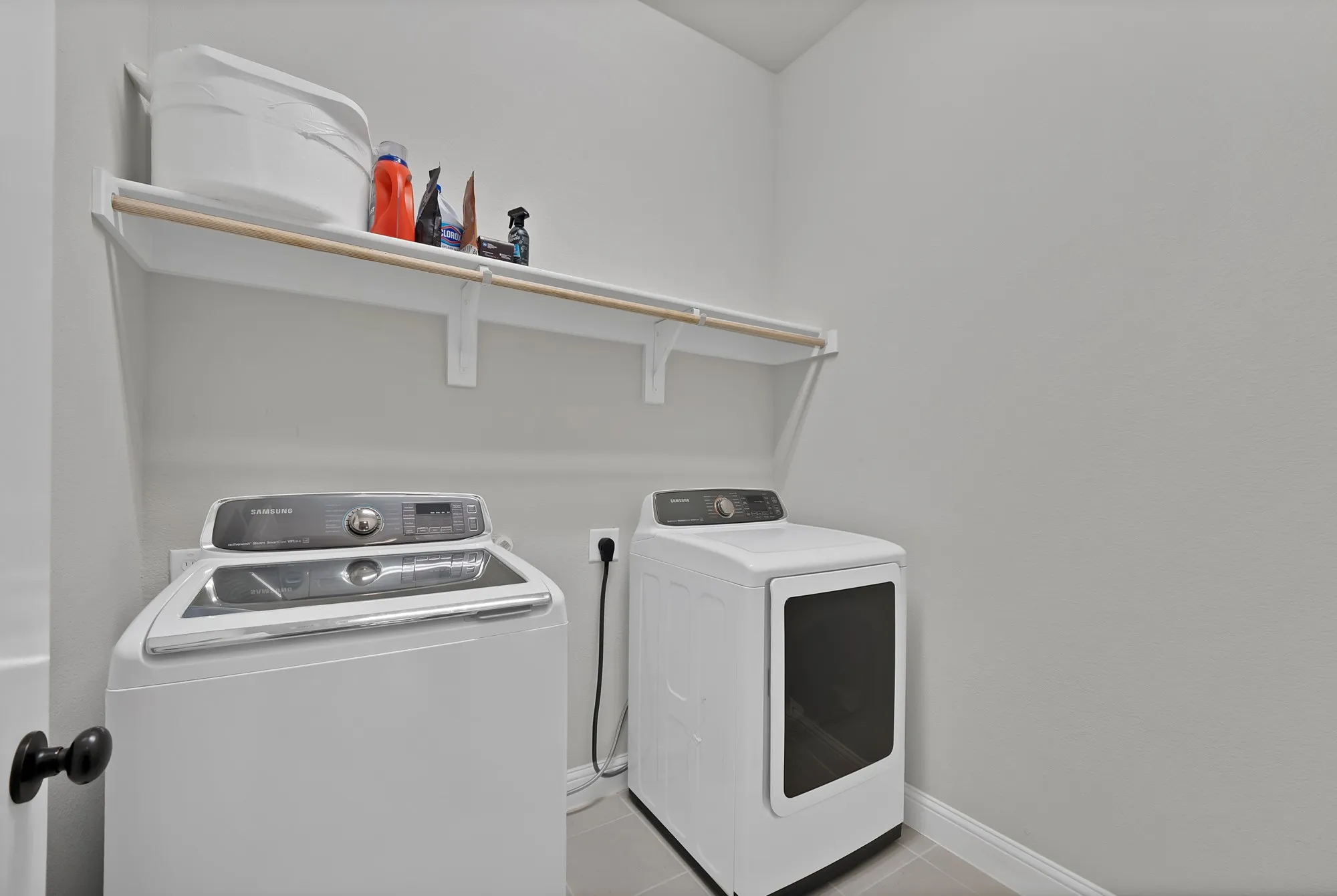 Dedicated laundry area featuring a white washing machine, dryer, and an overhead shelf