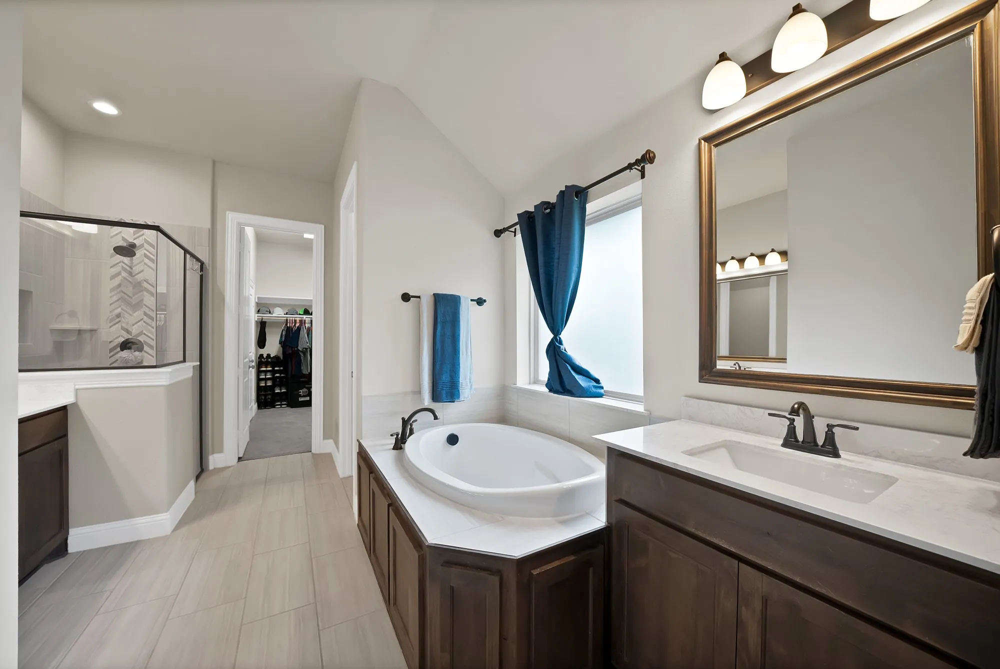 Well-appointed bathroom featuring a built-in tub, a large vanity with a rectangular sink, and a glass-enclosed shower with tiled walls