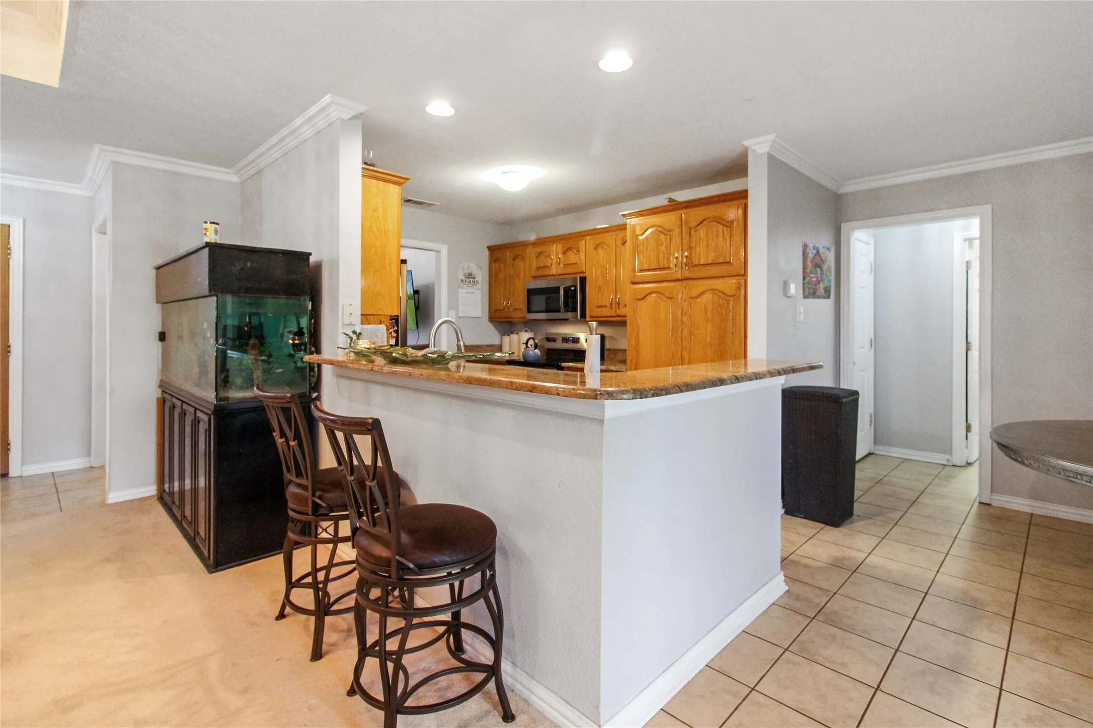 Kitchen featuring a granite-look countertop peninsula, wood cabinetry, stainless steel appliances, and recessed lighting