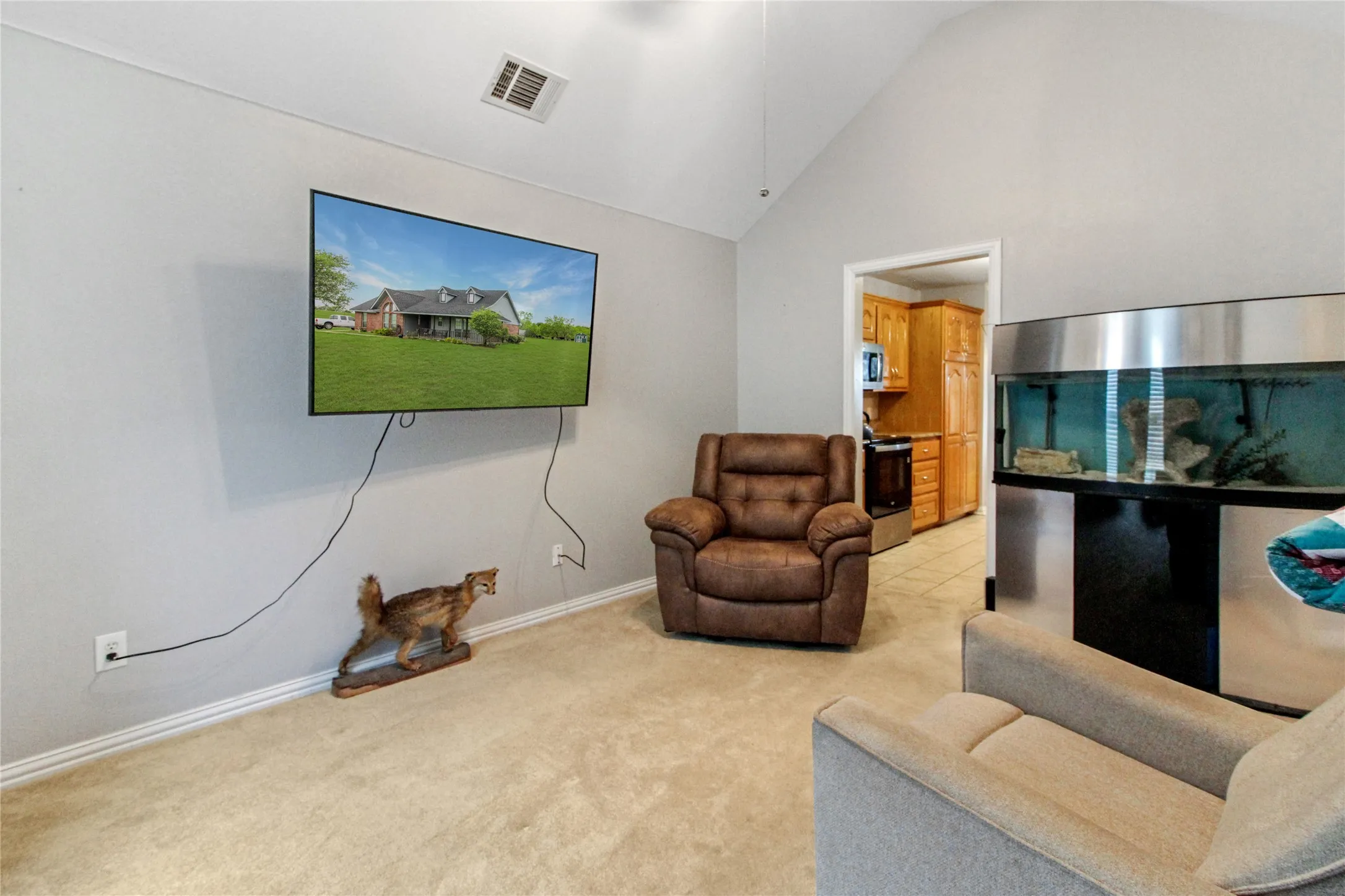 Vaulted ceiling with an air vent, light gray wall paint, and neutral carpet flooring