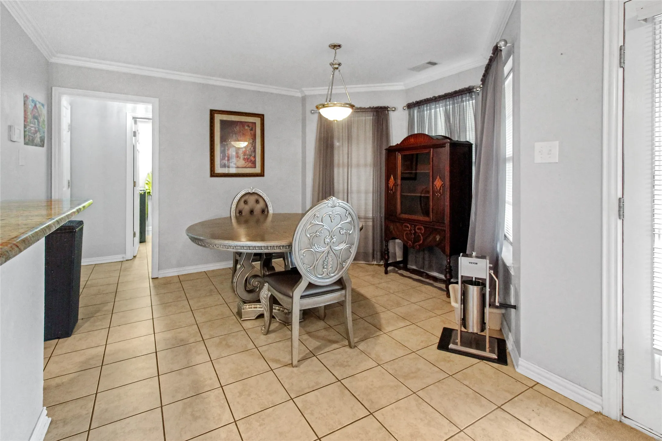 Dining area featuring tile flooring, a bay window with curtains, and a pendant light fixture