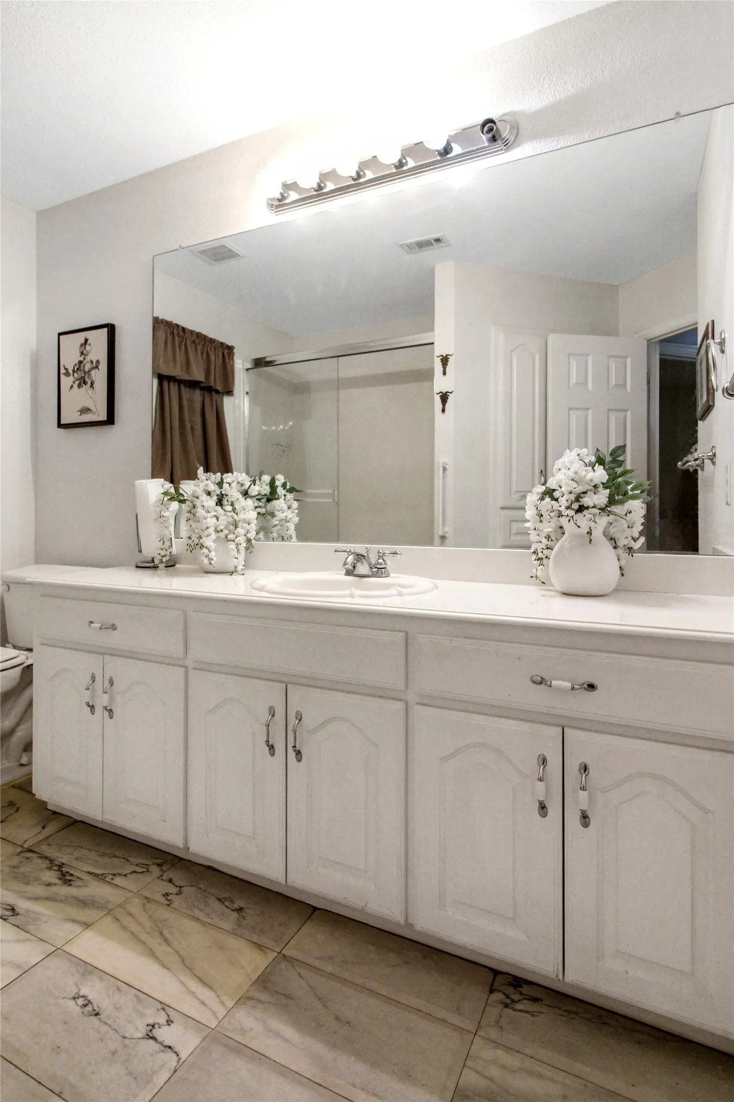 Vanity featuring an integrated sink with a chrome faucet, extensive countertop space, and white cabinetry