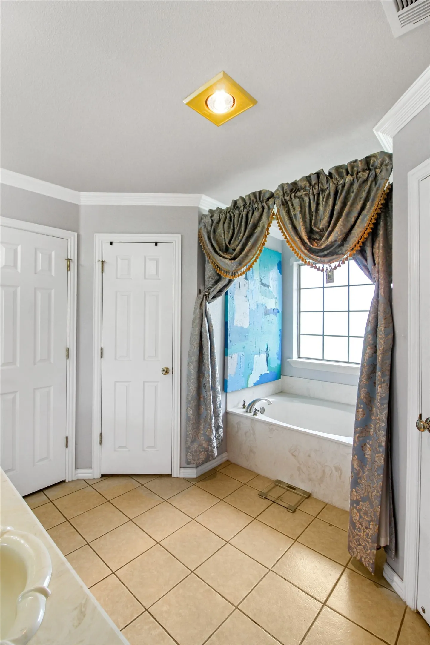 Soaking tub with a tiled surround, complemented by a window with decorative valances and drapes