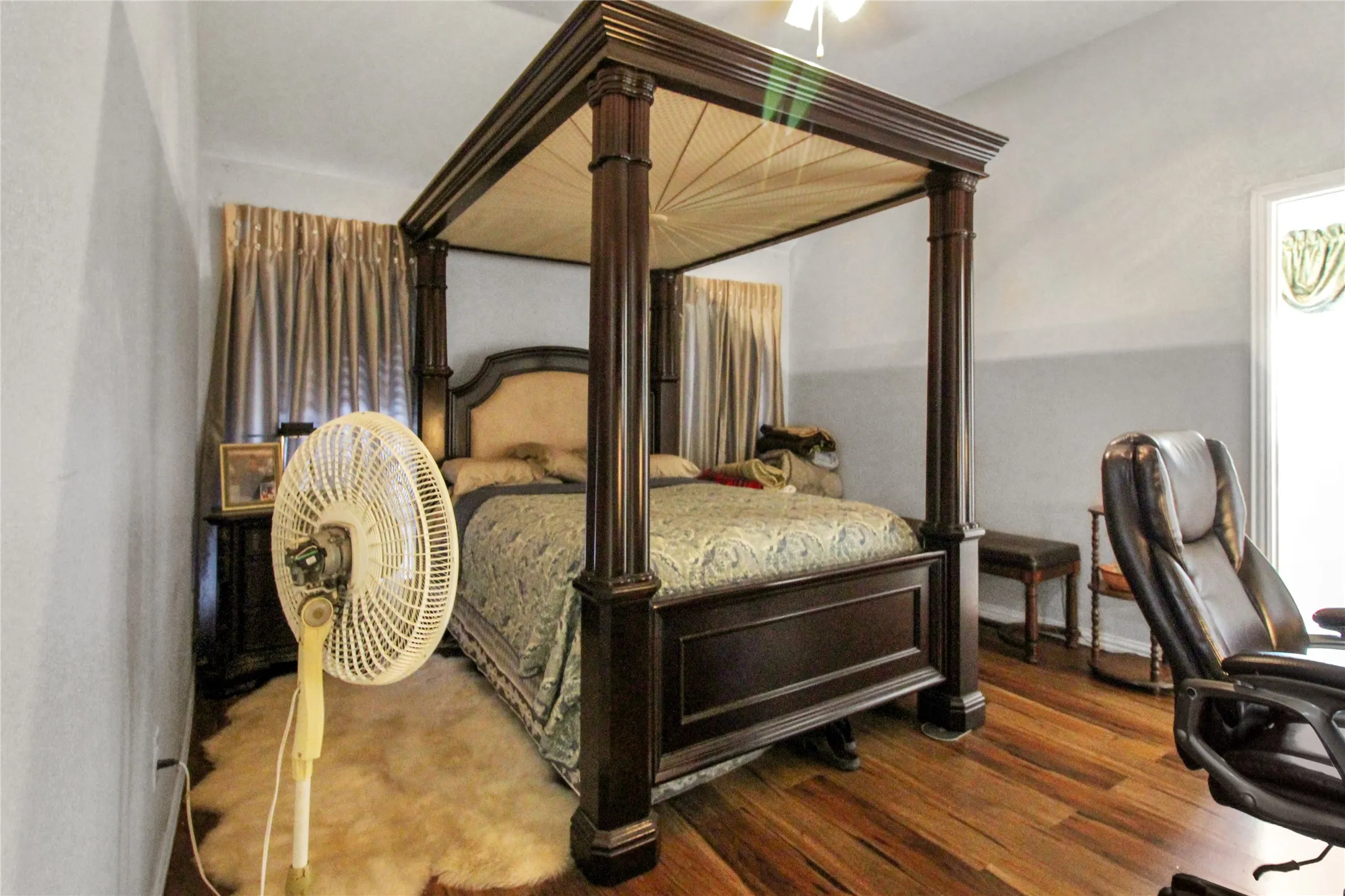 Wood-finish flooring throughout, featuring light gray wall paint and a window with green valance