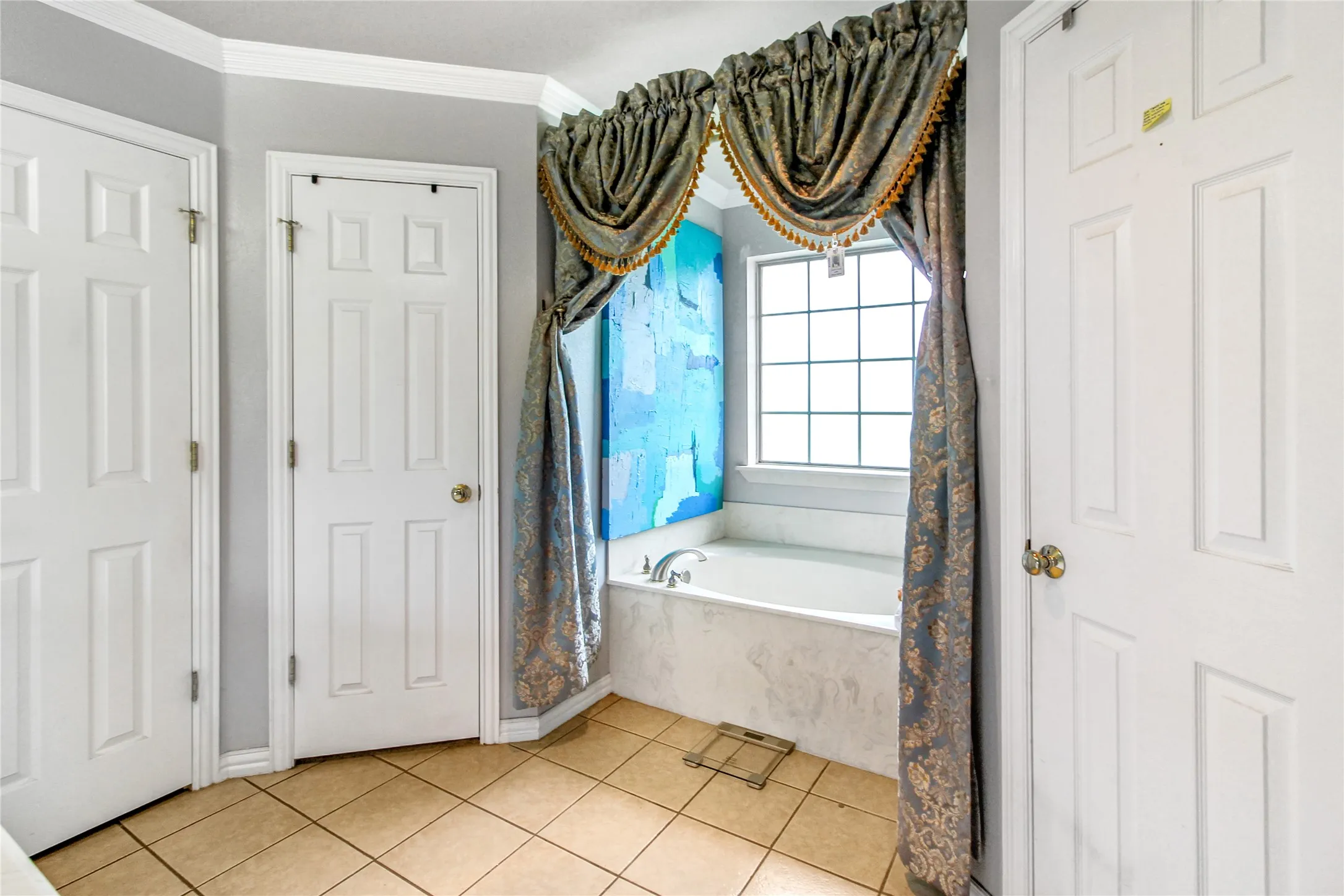 Soaking tub with a grid window, light tile flooring, and multiple six-panel doors