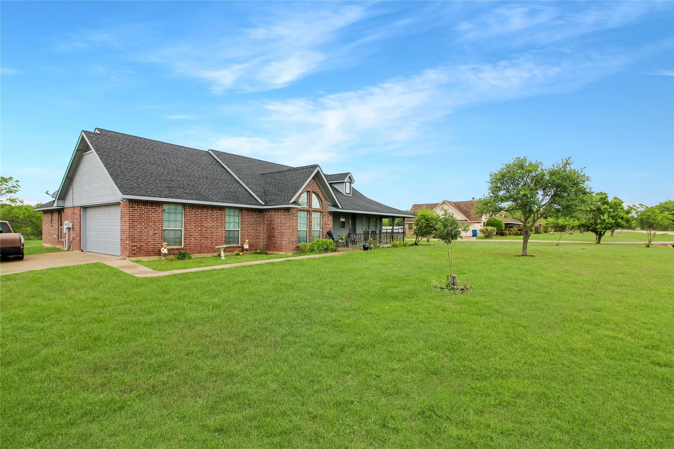 Brick and siding exterior featuring an attached garage, covered front porch, and a dormer window