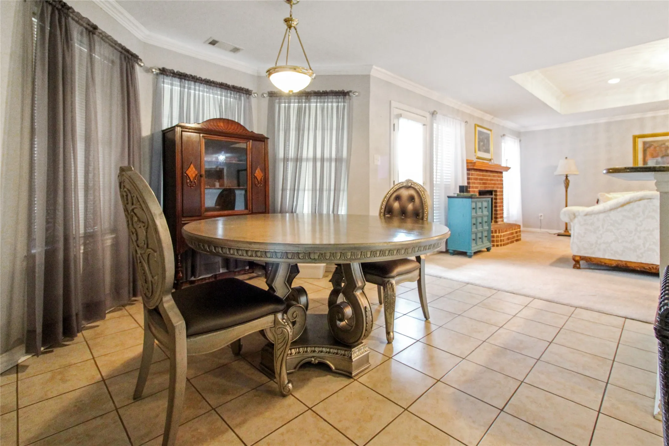 Tiled flooring extending into a combined living area featuring a brick fireplace