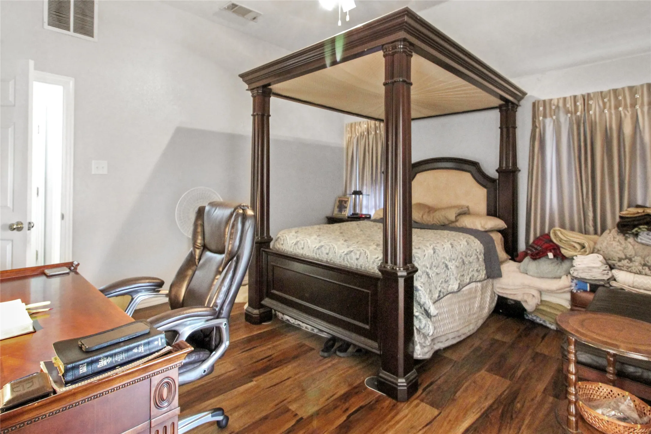 Spacious room featuring wood-finish flooring, vaulted ceiling, and white painted walls