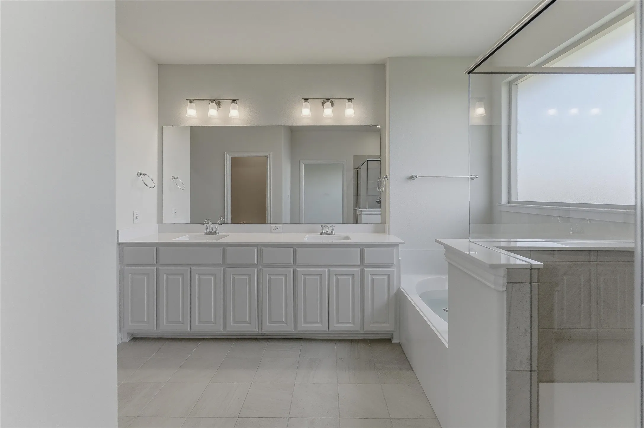 Bathroom featuring a double vanity with ample cabinetry, dual undermount sinks, and a substantial mirror