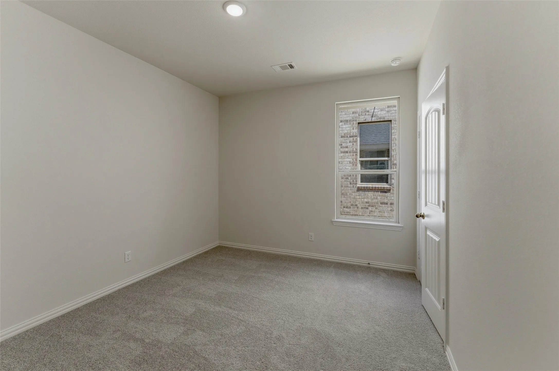 Neutral-toned room featuring a single window with exterior brickwork visible