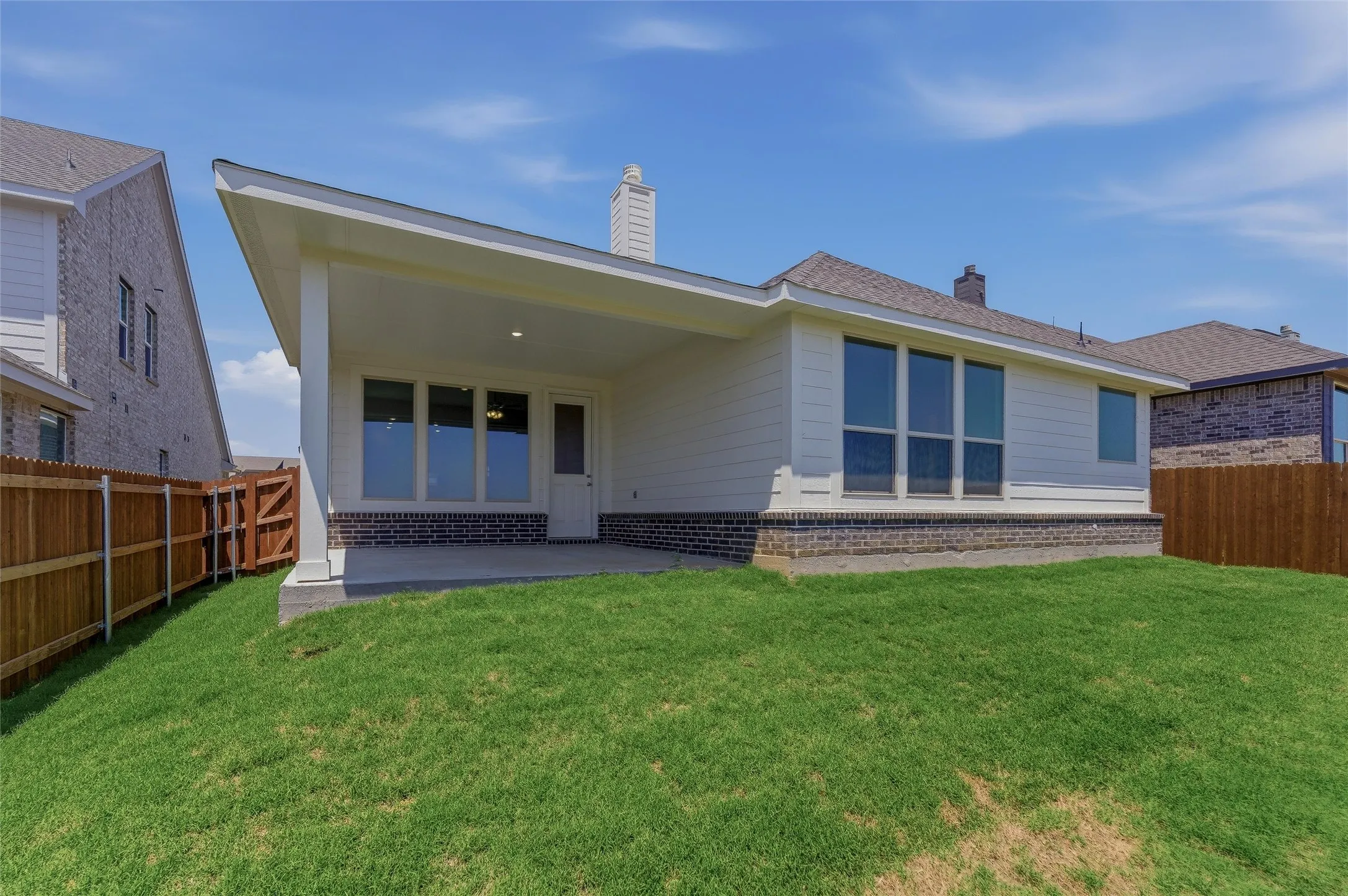 Rear exterior featuring a covered patio, extensive window placements, and a wood privacy fence