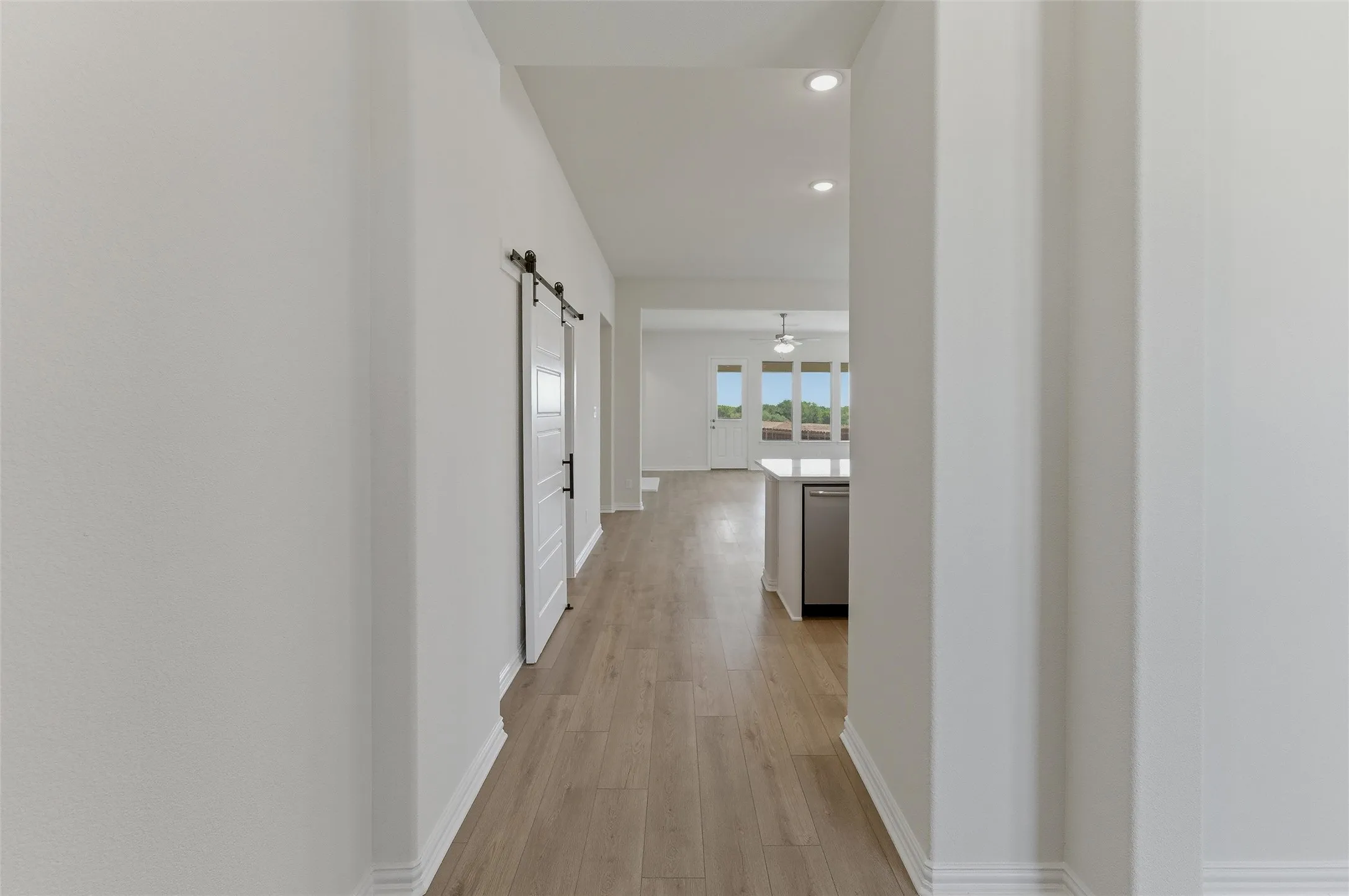 Hallway featuring wood-finish flooring, recessed lighting, and a white barn door with black hardware