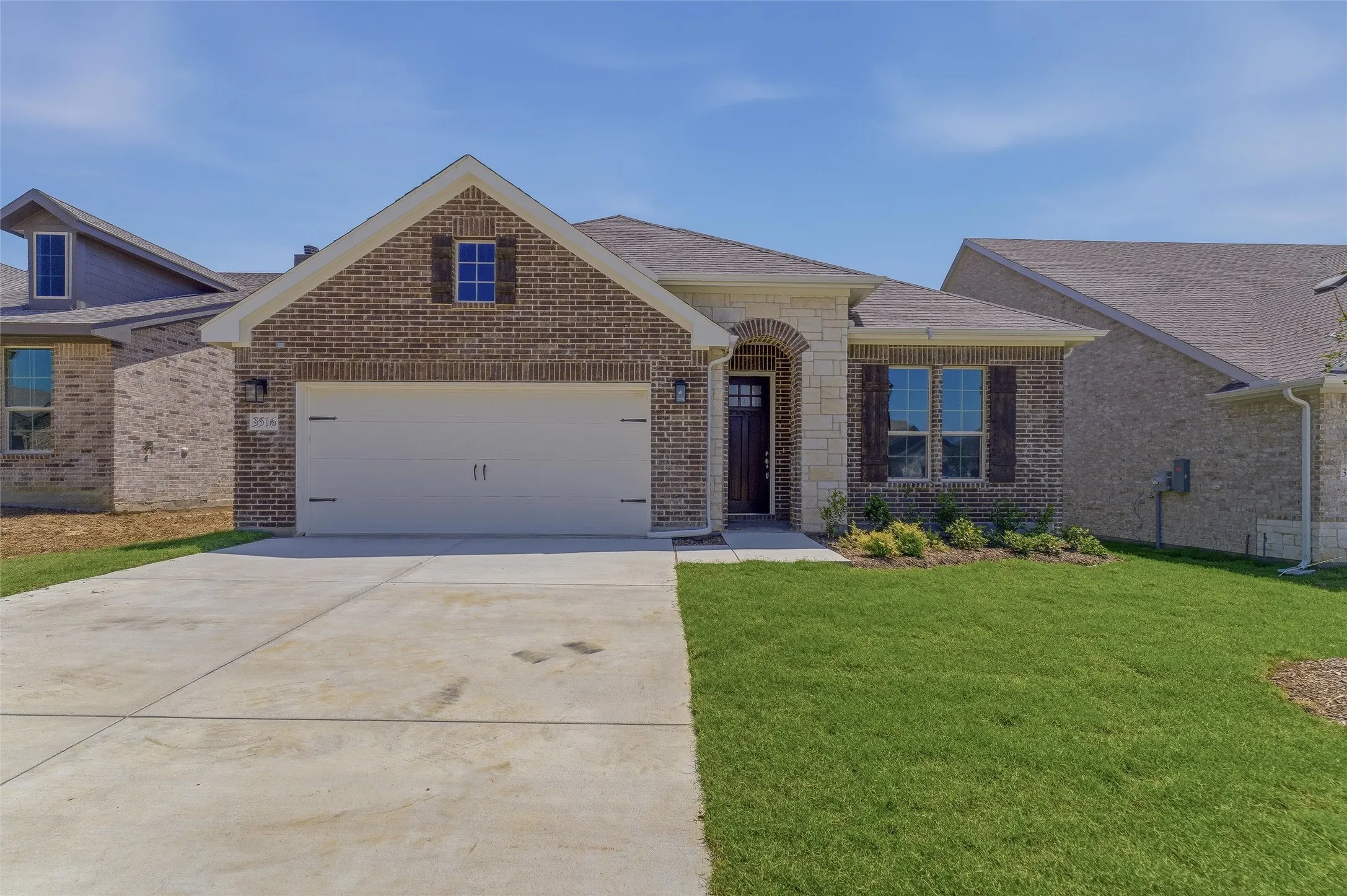 Brick and stone exterior featuring an arched entryway and dark wood front door