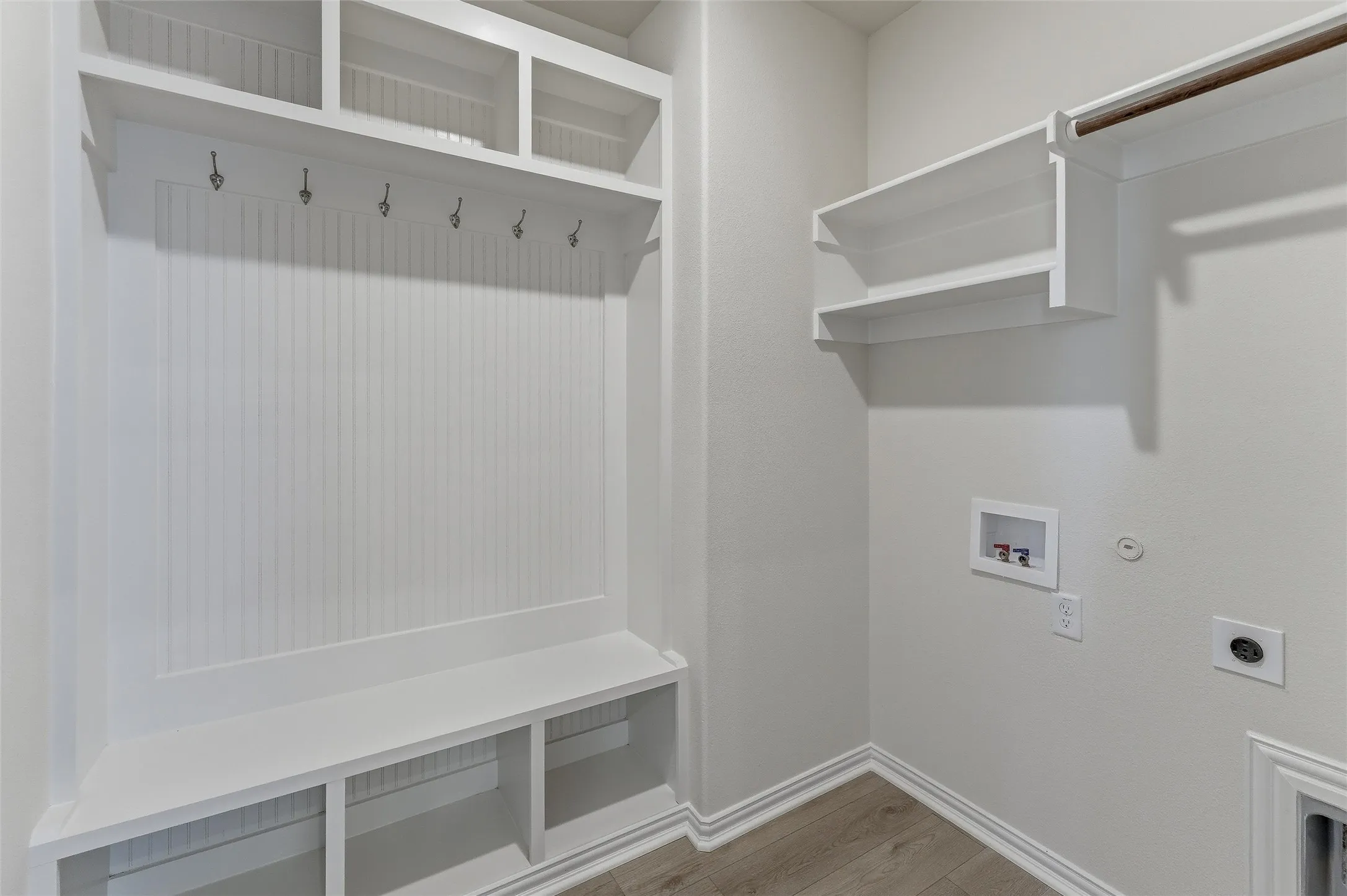 Mudroom featuring built-in white cabinetry with beadboard paneling, integrated bench seating, and overhead storage cubbies