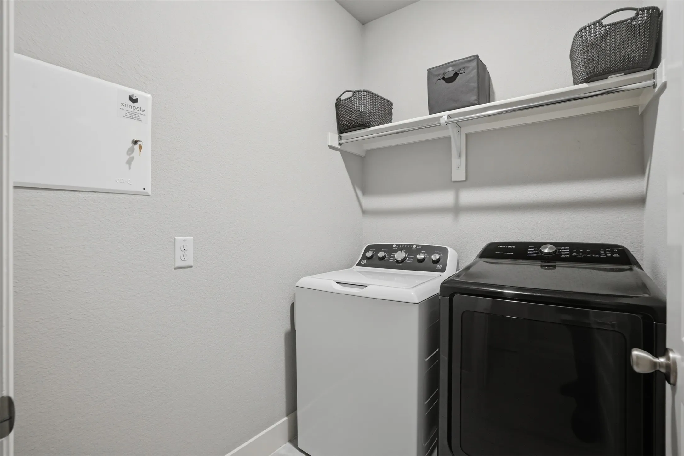 Dedicated laundry area featuring a white top-load washing machine and a black front-load dryer