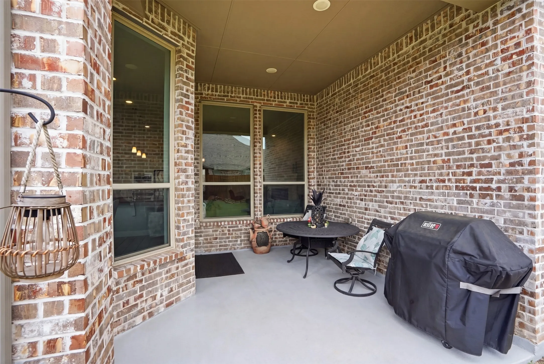 The property features a covered patio with brick walls, an outdoor ceiling, and windows
