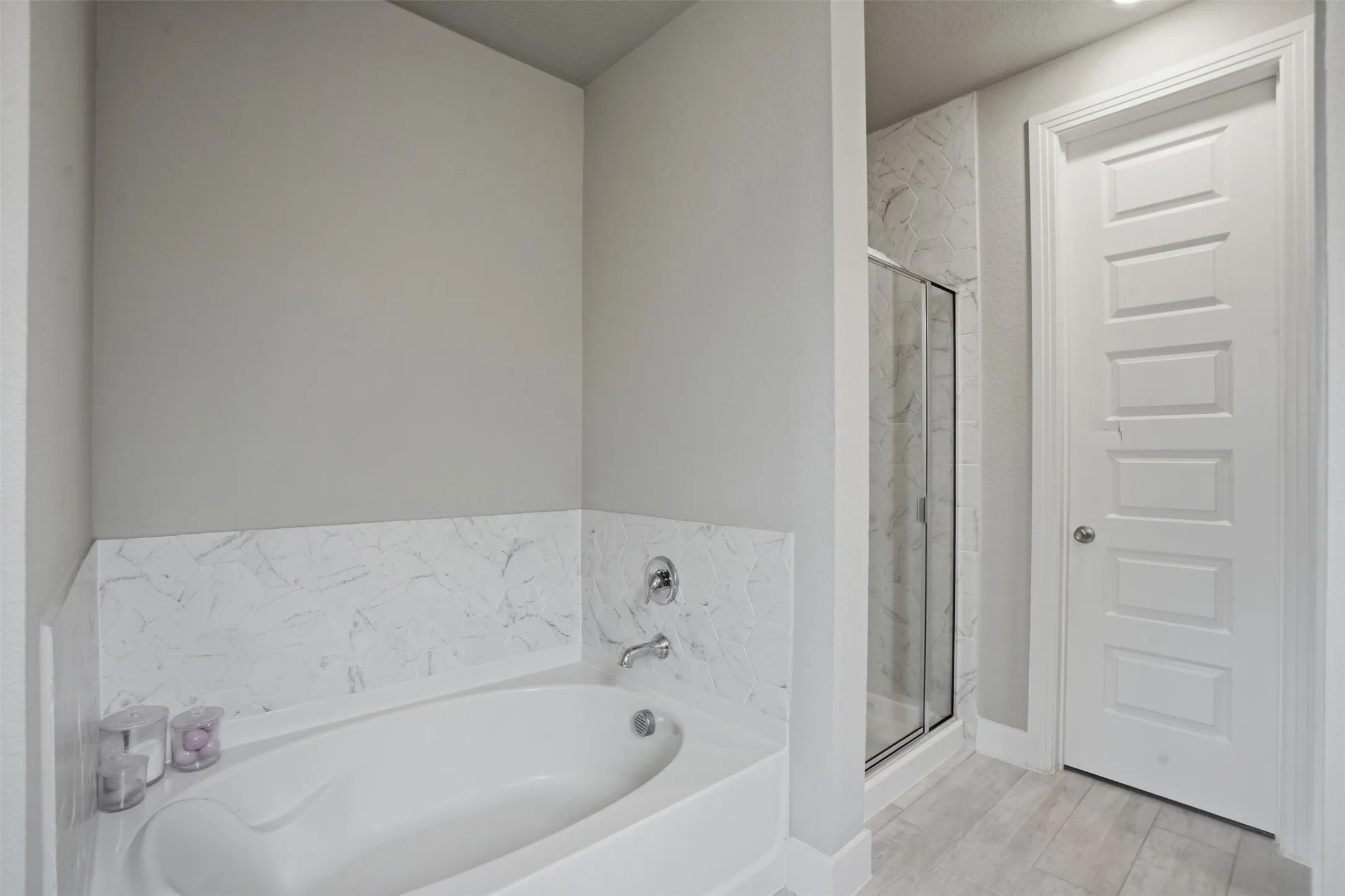 The bathroom features a built-in tub with a tiled surround, a separate glass-enclosed shower, and a paneled door