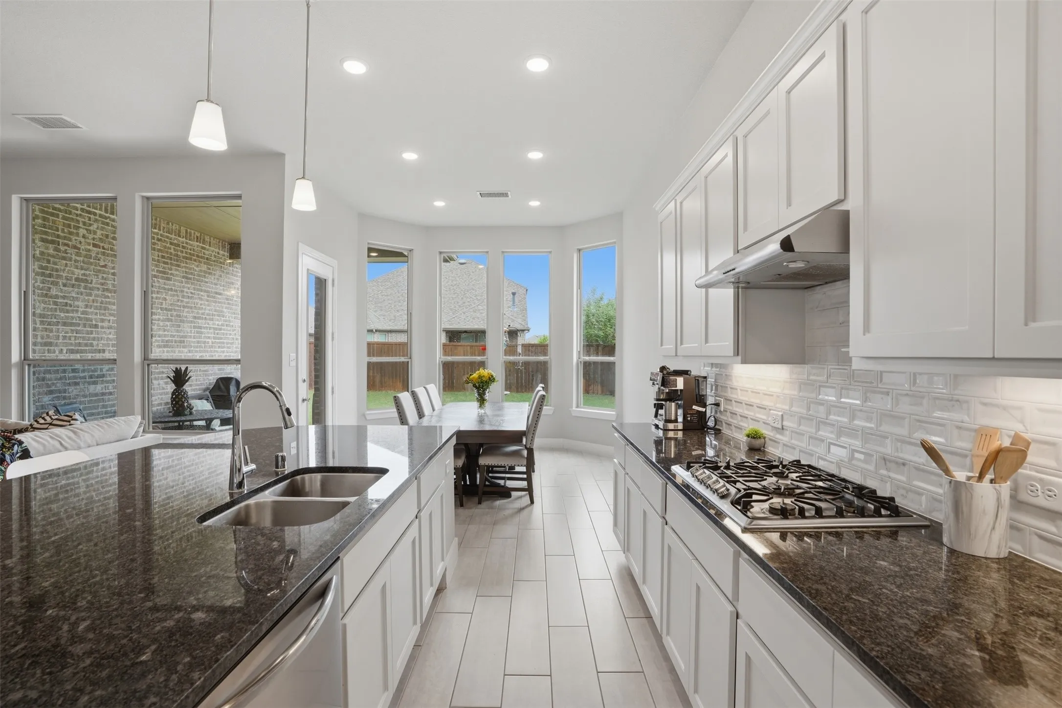 The kitchen features a gas cooktop, white cabinetry, dark countertops, and a double sink