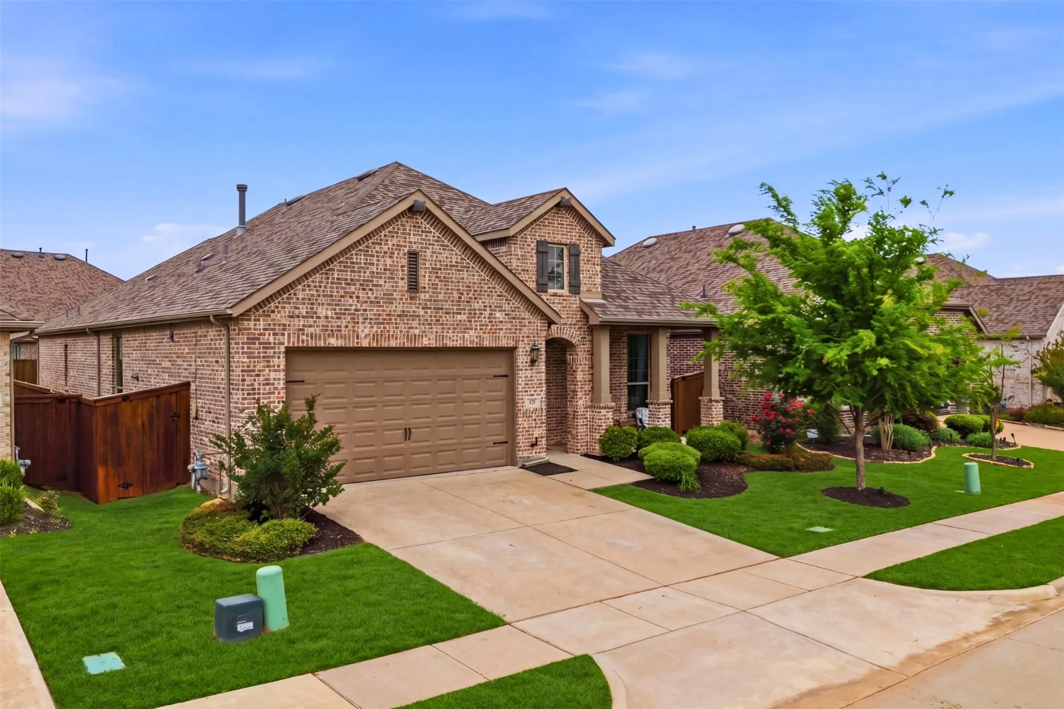 The property features a brick exterior, an attached garage, a well-maintained lawn, and mature landscaping