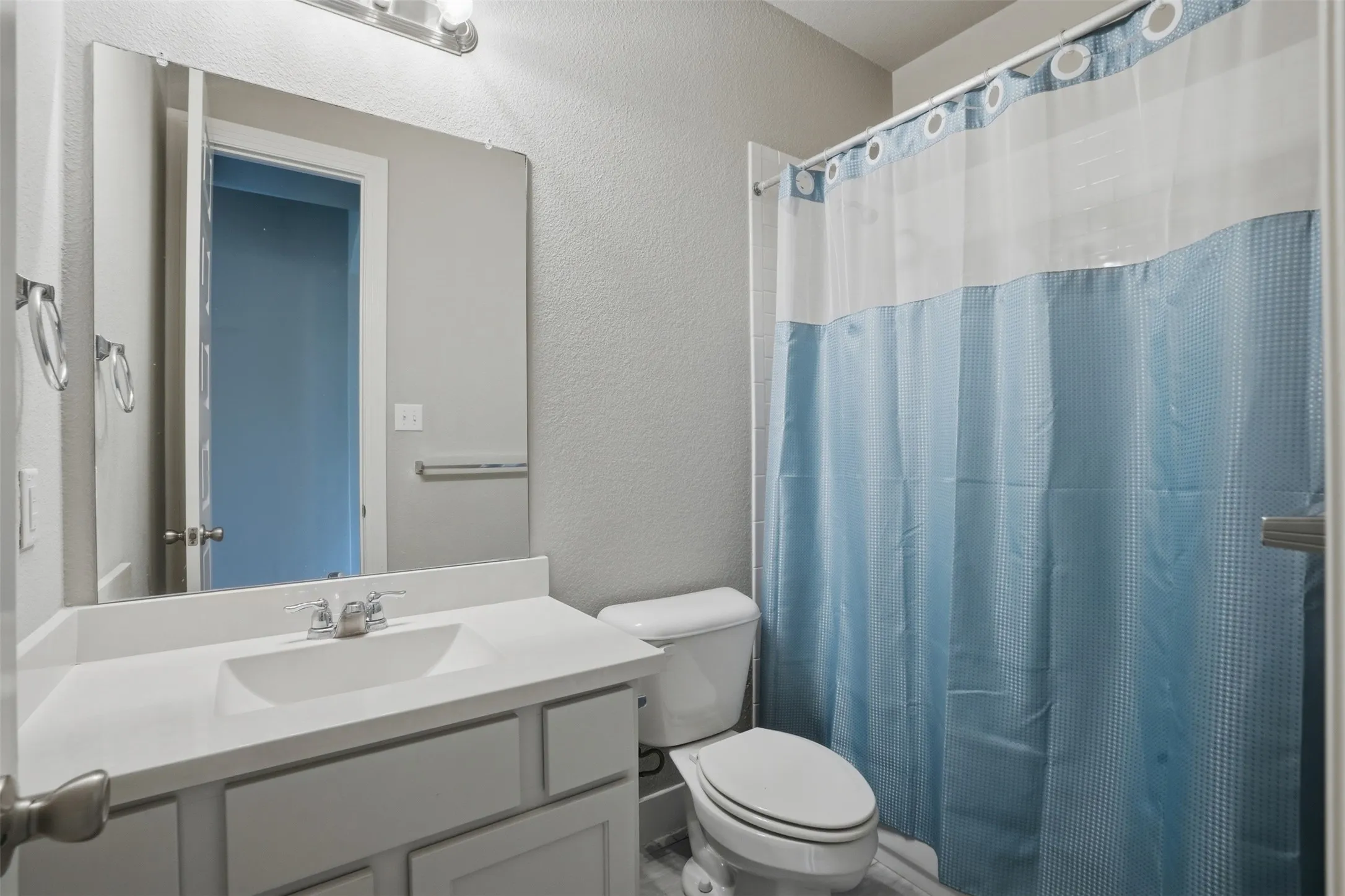 Bathroom featuring a vanity with an integrated sink, a mirror, and a toilet