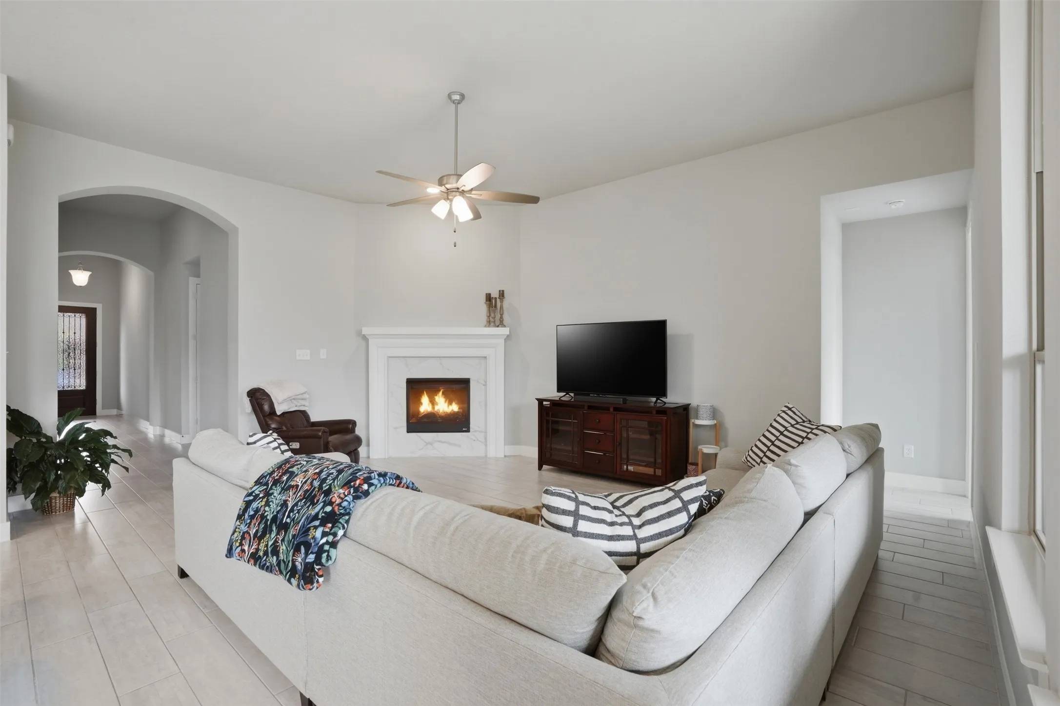 The living room features light-colored flooring, a fireplace with a white mantel, and a ceiling fan