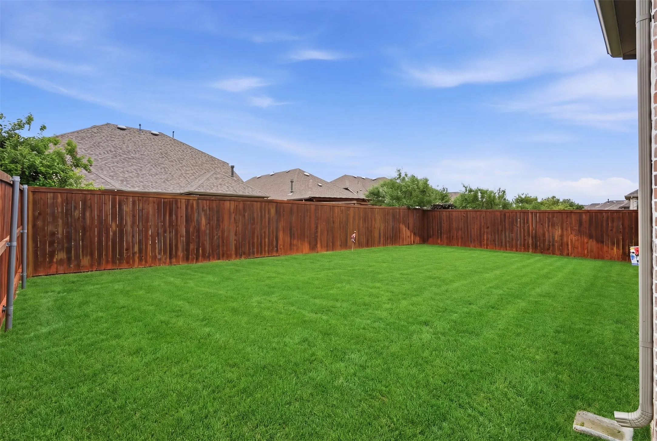 The property features a spacious backyard with a well-maintained lawn, enclosed by a wooden privacy fence