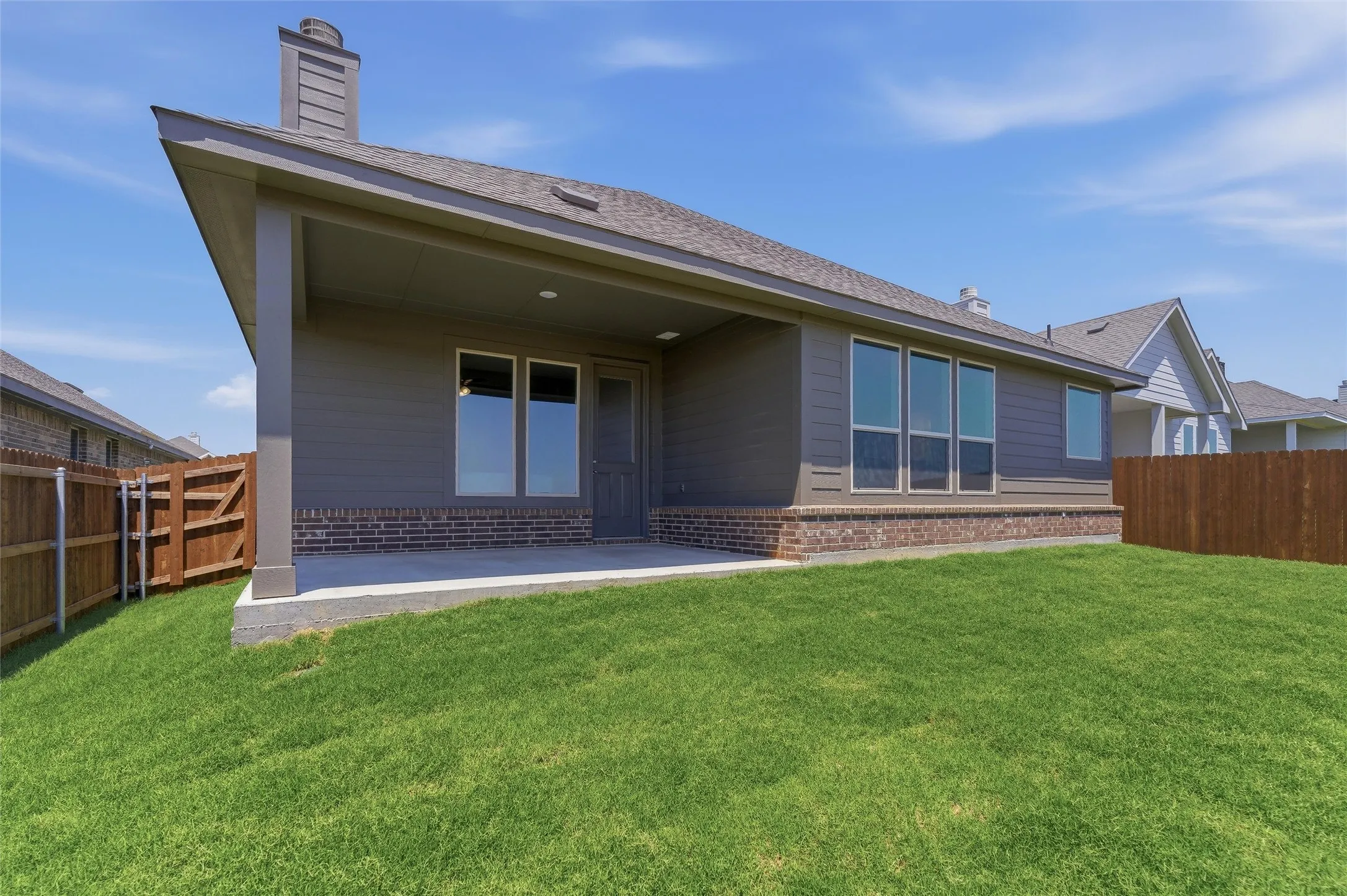 Expansive backyard featuring a covered patio, a manicured lawn, and a privacy fence