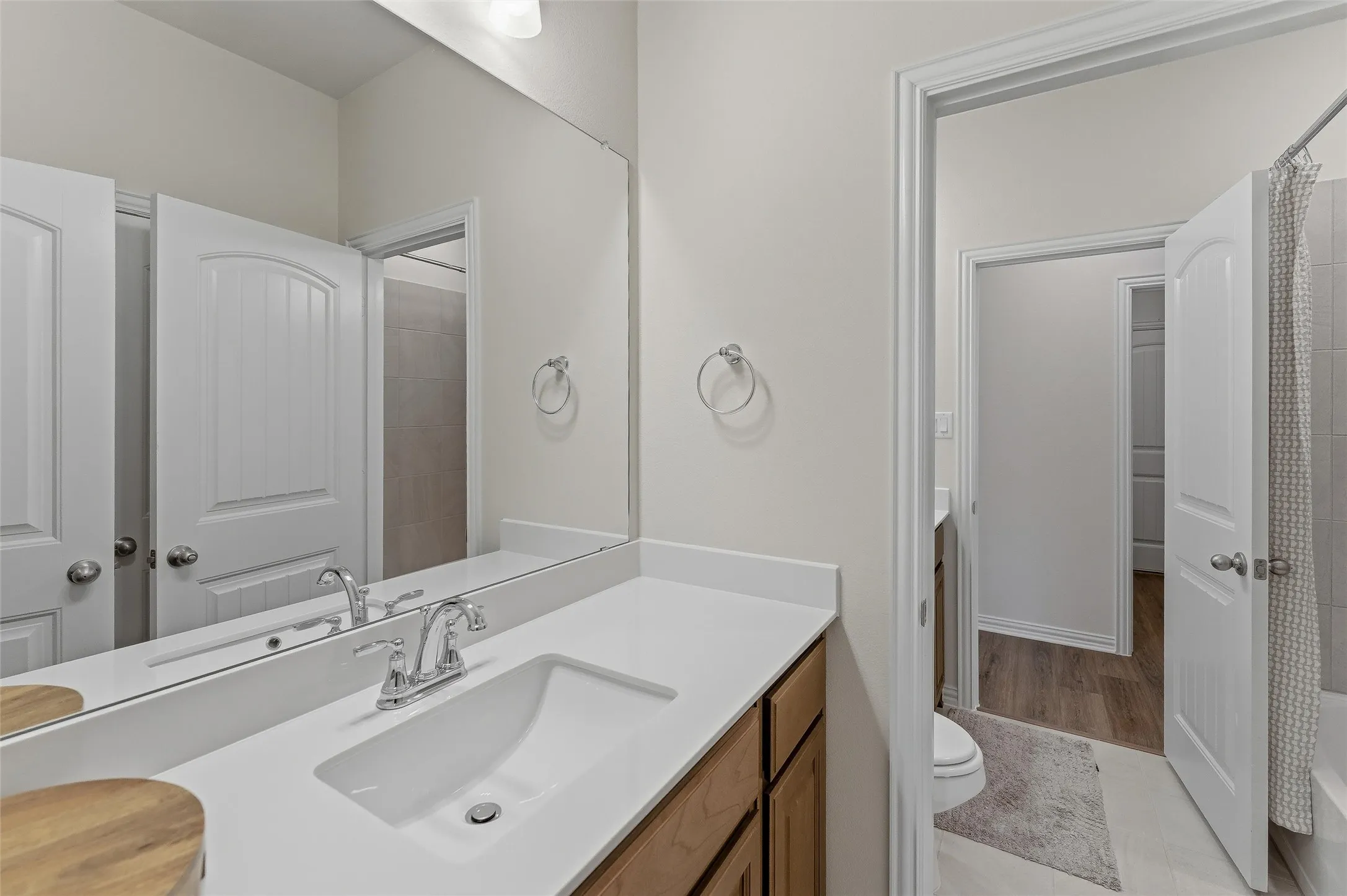 Bathroom vanity featuring a single basin sink, chrome faucet, and expansive wall-mounted mirror