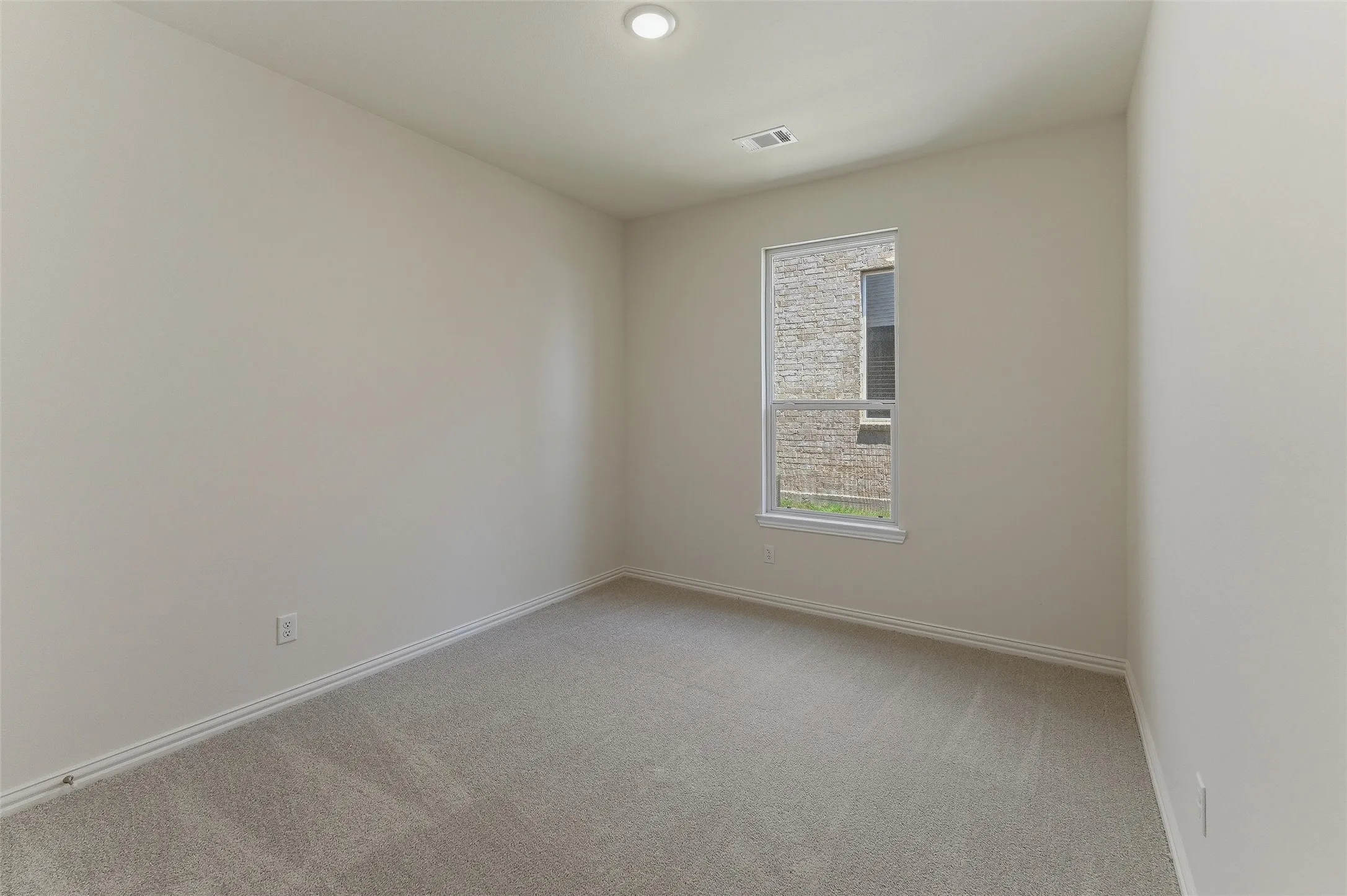 Carpeted interior room featuring a window with exterior stone cladding visible, recessed ceiling light, and baseboard trim