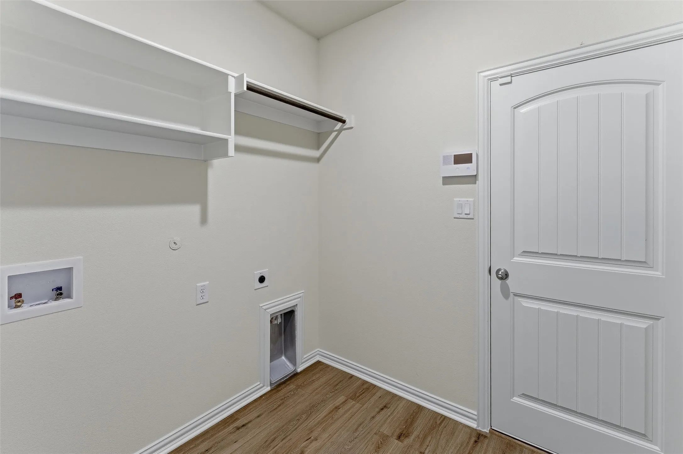 Utility space featuring wood-finish flooring, white baseboards, and light neutral wall paint