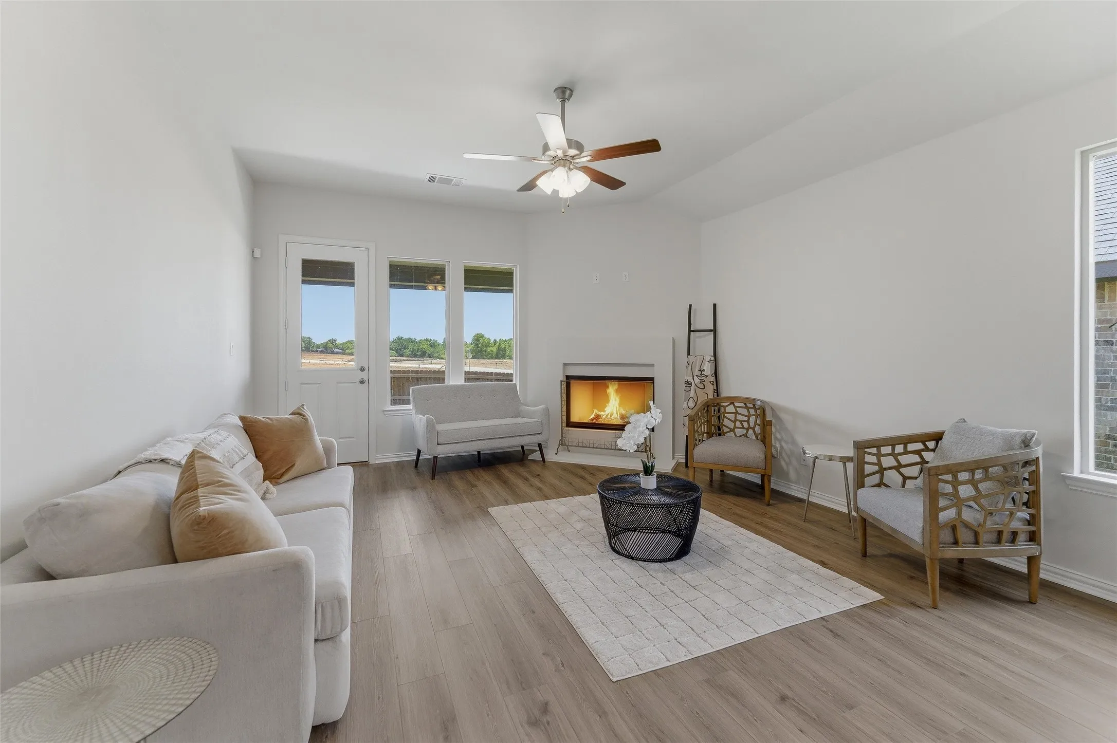 Spacious living area featuring wood-finish flooring, a corner fireplace, and a ceiling fan