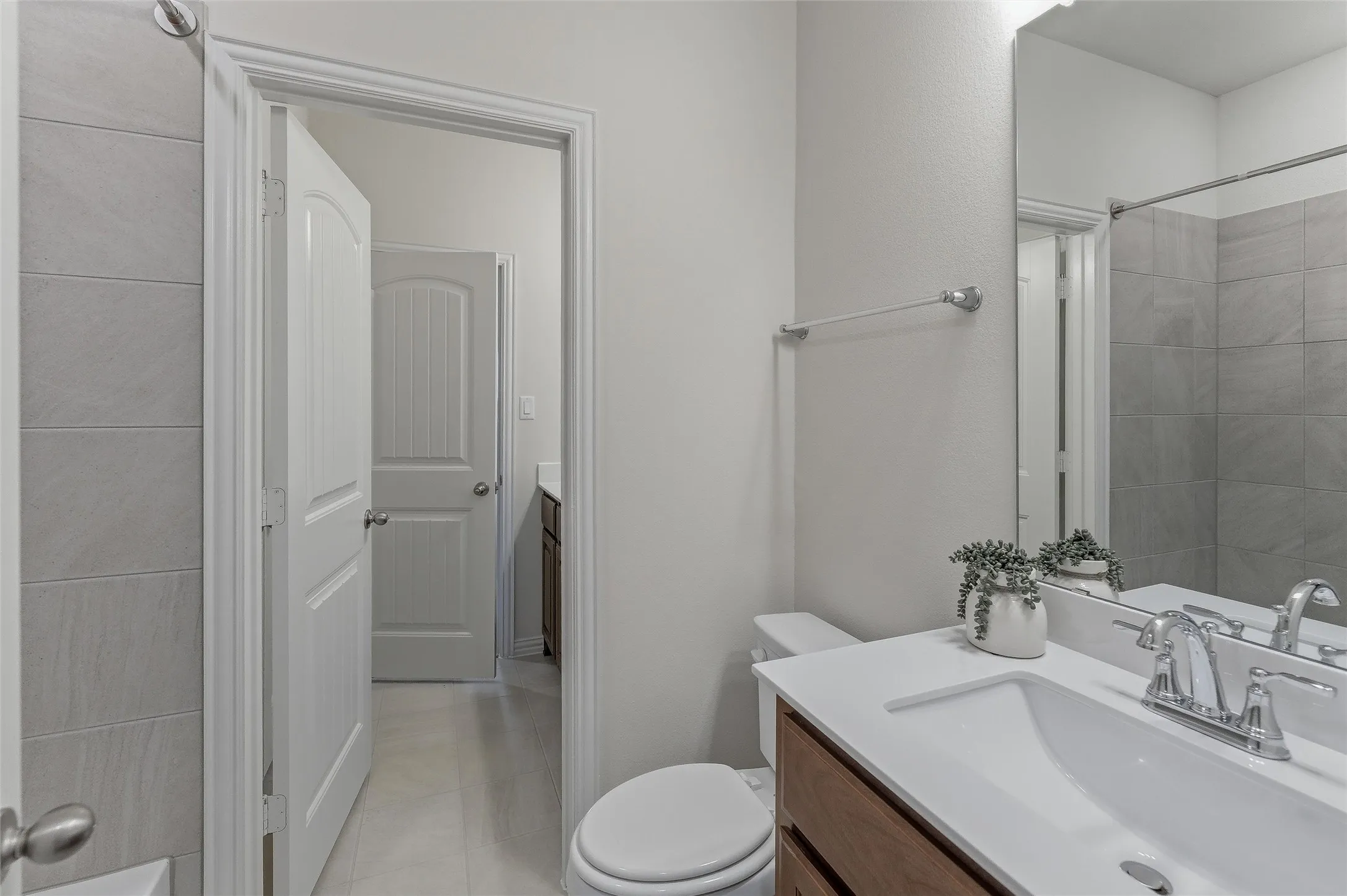 Bathroom featuring a single vanity with a white countertop and rectangular sink, polished chrome faucet, and wood-finish cabinetry