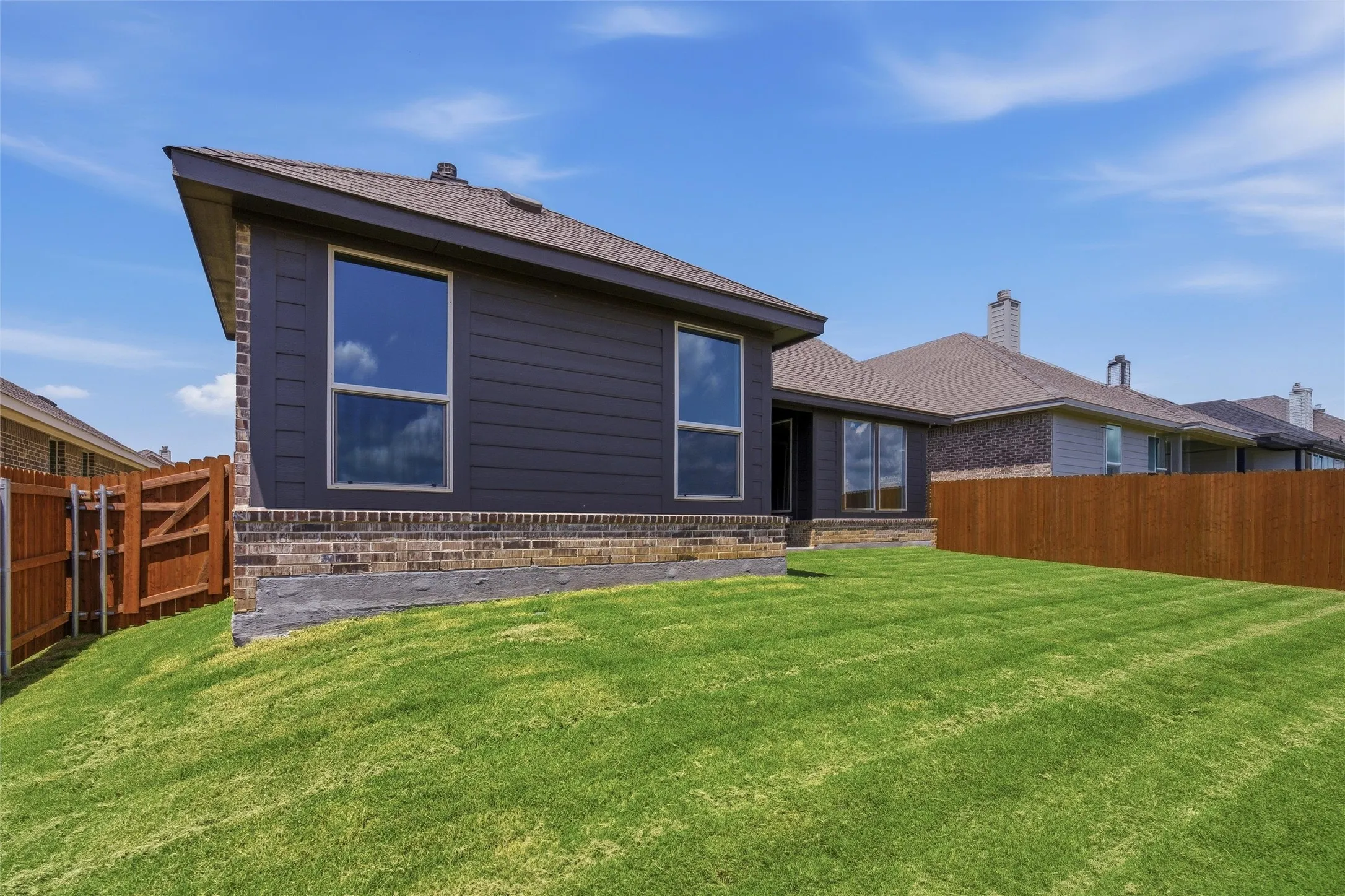 Expansive green lawn with a newly installed wooden privacy fence