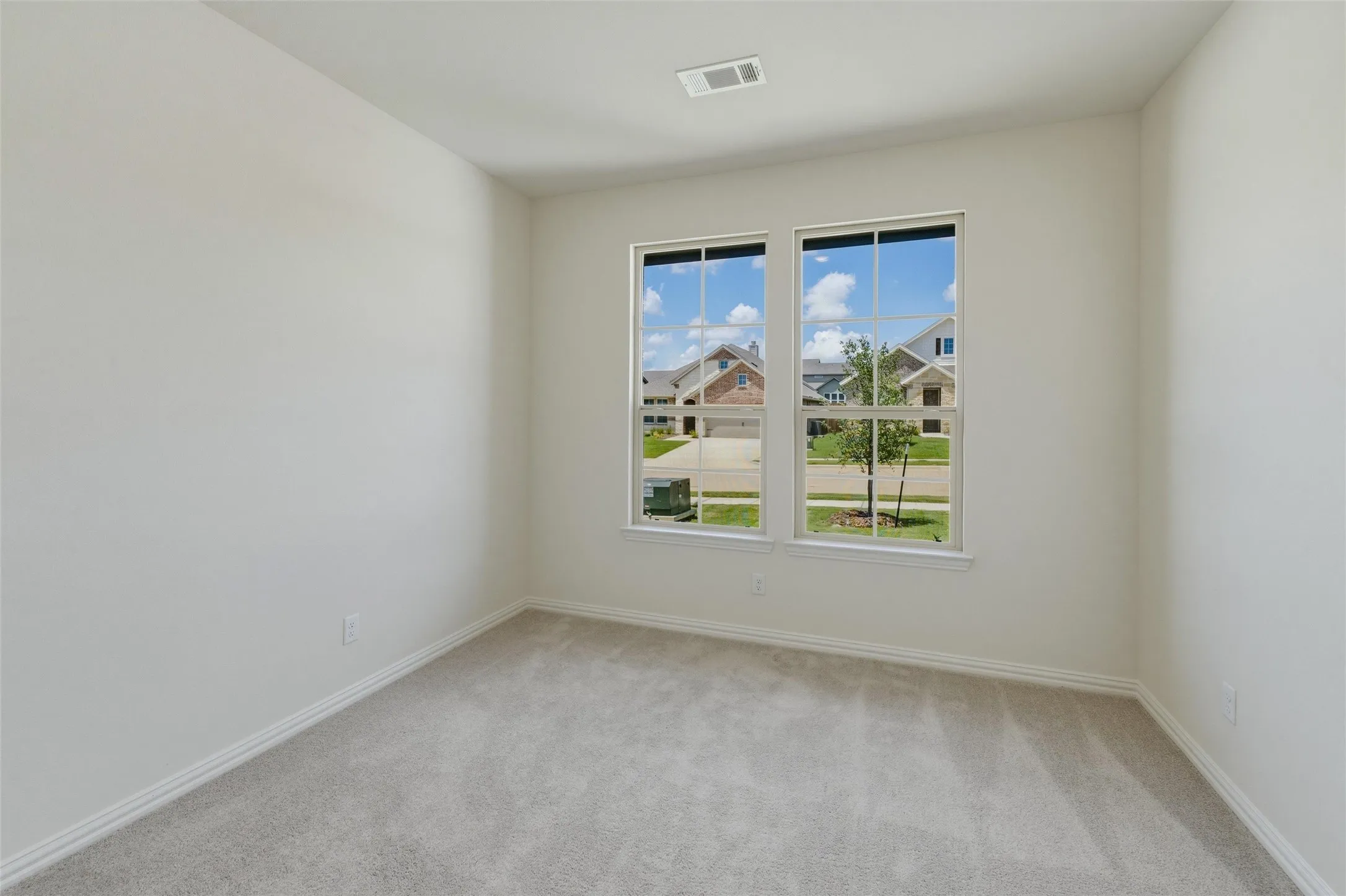 Windowed interior space featuring light gray carpeting and white painted walls