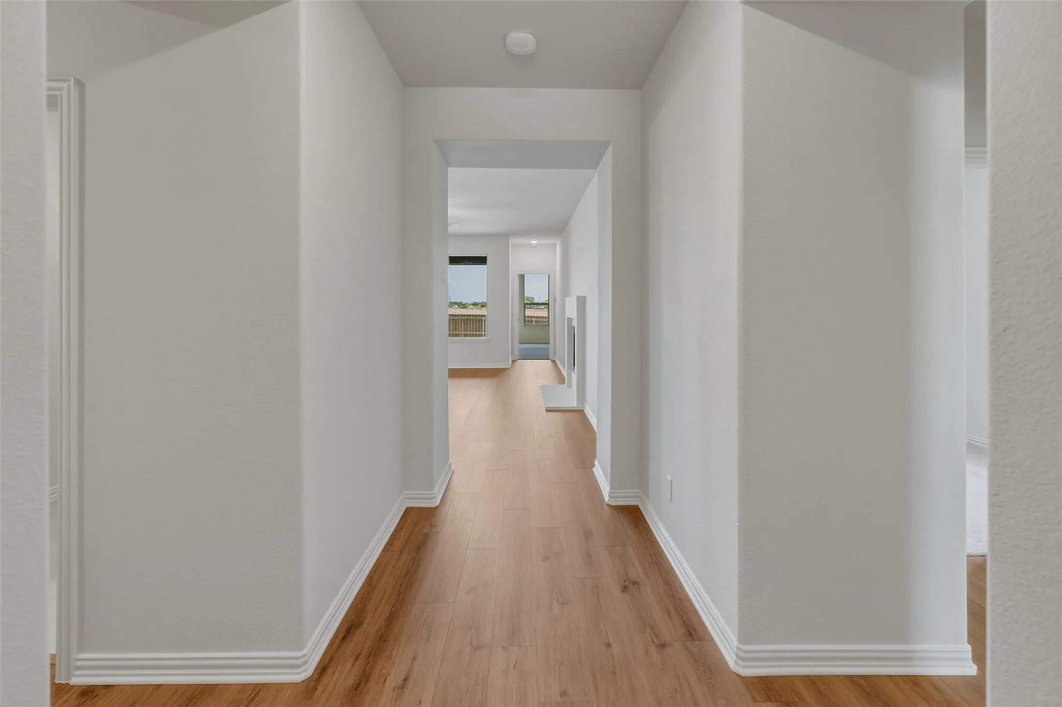 Hallway with wood-finish flooring, crisp white baseboards, light neutral wall tones, and recessed lighting