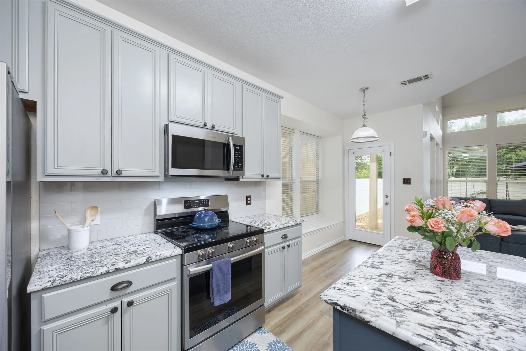 Kitchen featuring light gray cabinetry, stainless steel appliances, and granite countertops