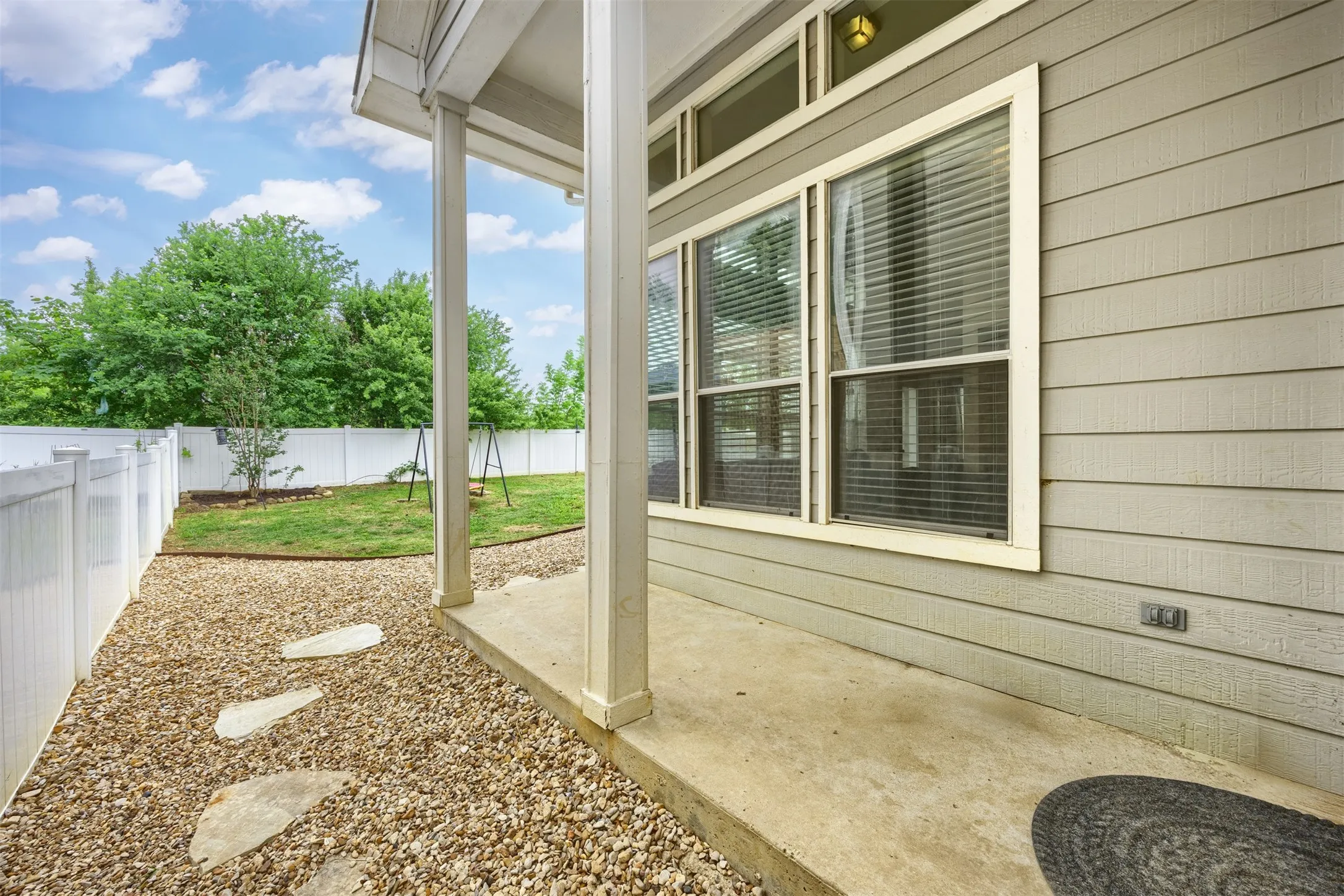 The property features a private fenced yard with a lawn, mature trees, and a gravel path with stepping stones