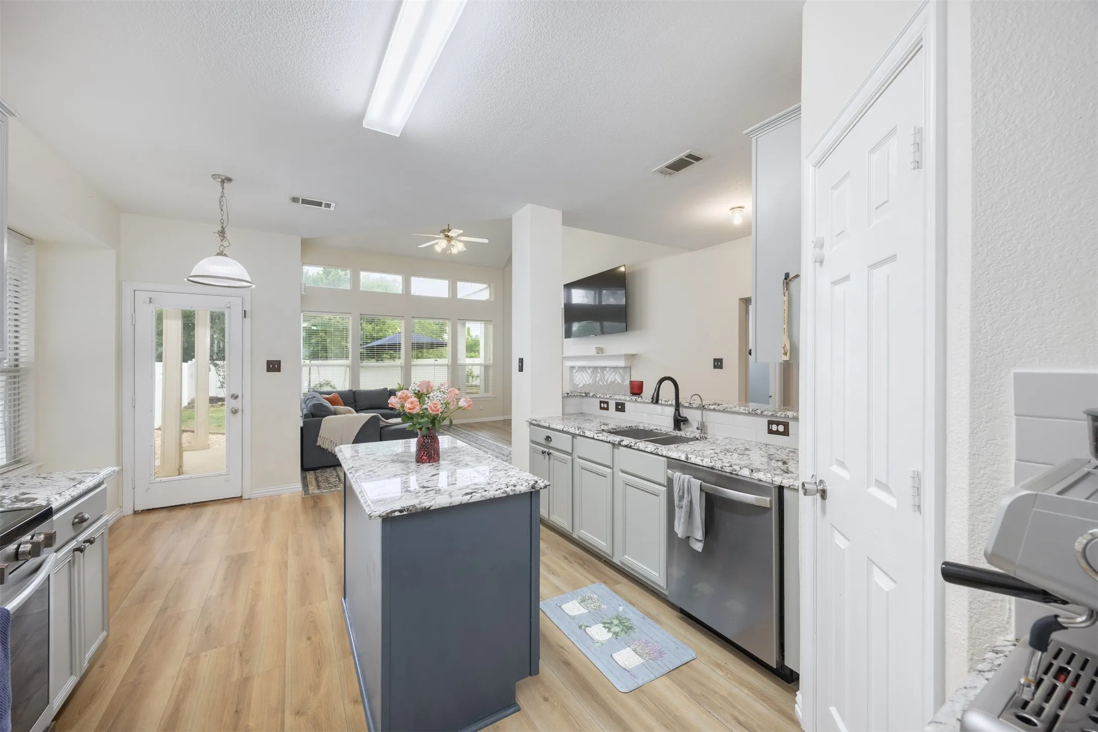 The kitchen features a center island with a granite countertop, light wood-style flooring, and stainless steel appliances