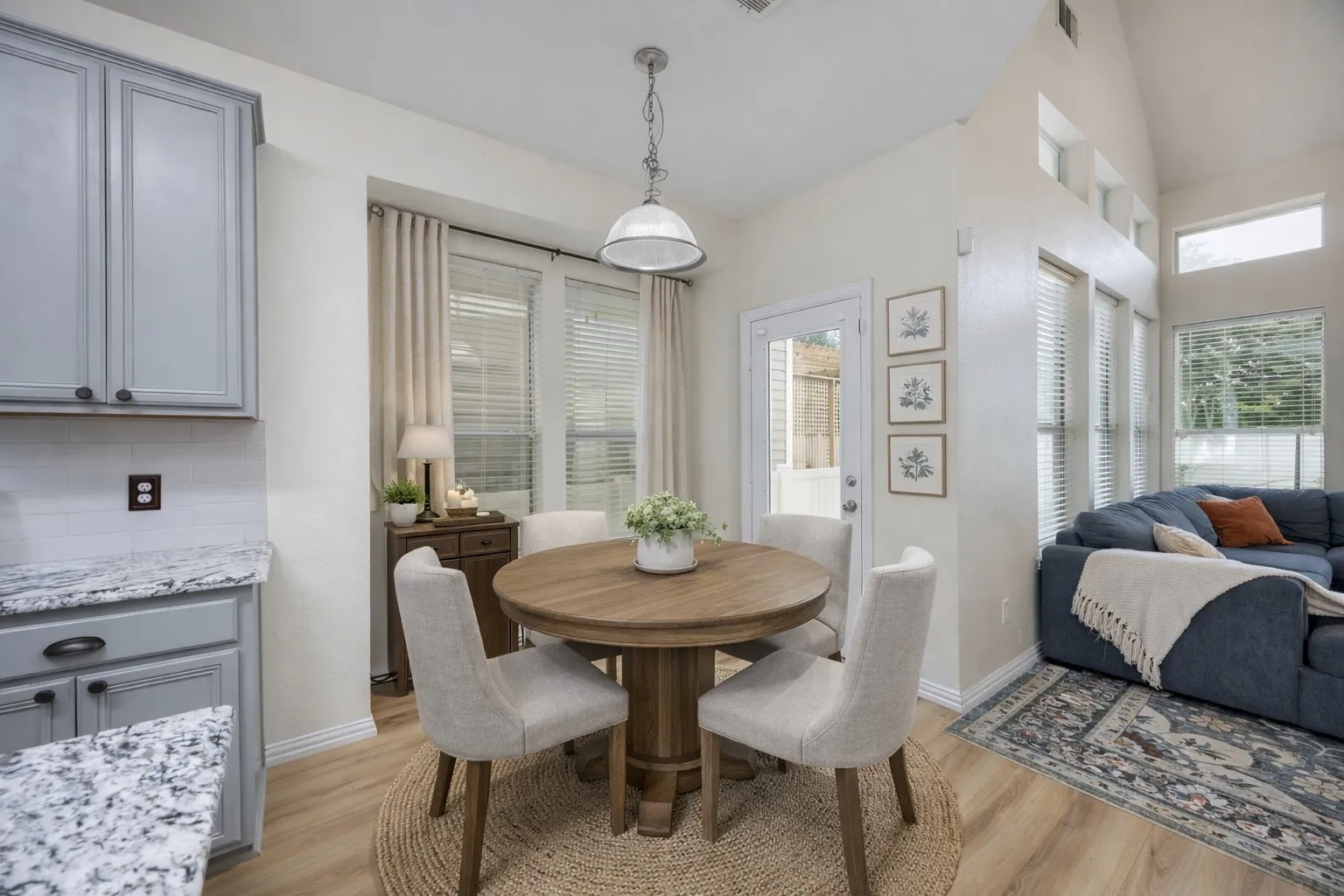 This dining area features a round wooden table, seating for four, and light wood-style flooring