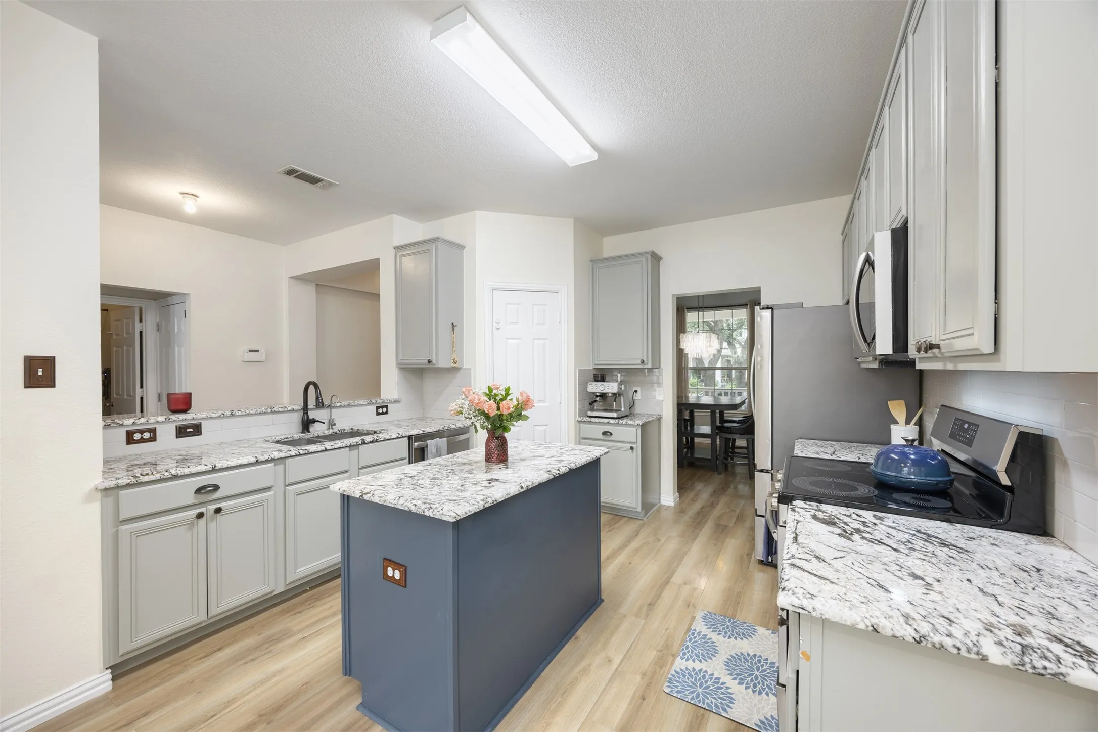 The property features a kitchen with light-colored cabinetry, granite countertops, and wood-look flooring
